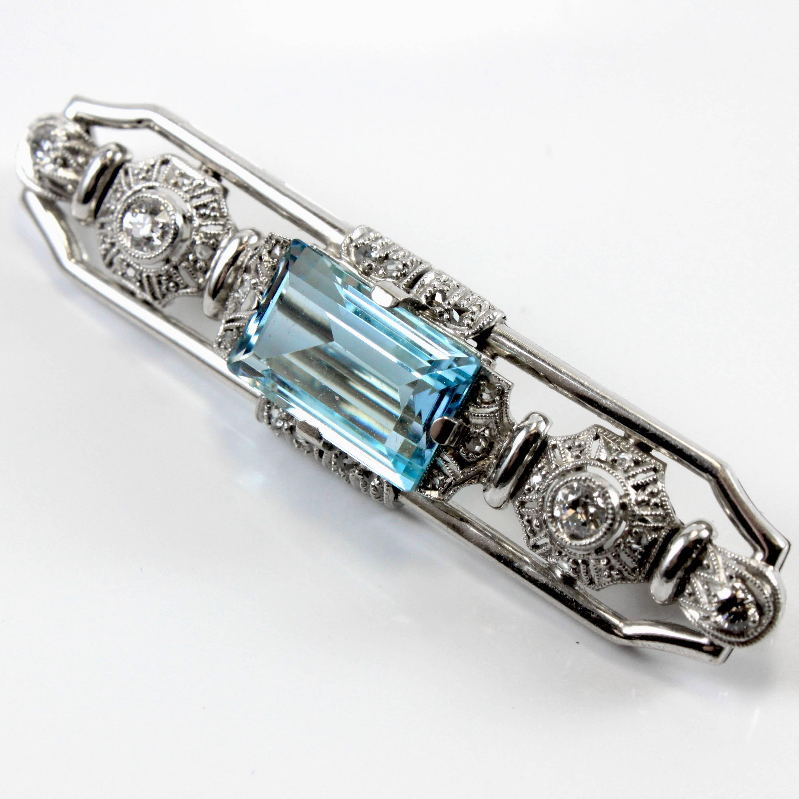 An Art Deco brooch from 1920s in white gold, centring a facetted aquamarine and accentuated my round brilliant cut diamonds. 