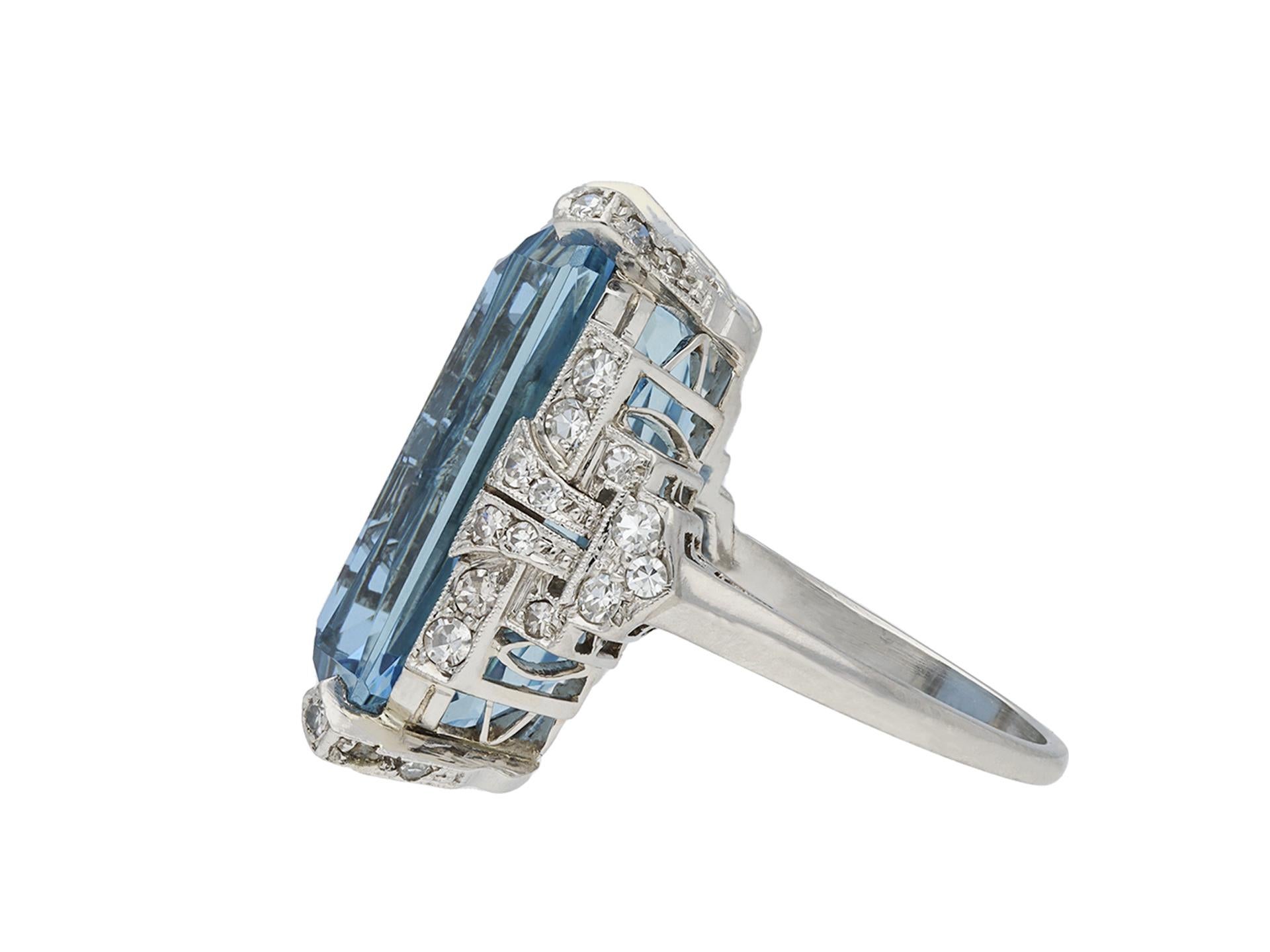 Art Deco aquamarine and diamond ring. Centrally set with an octagonal scissor cut natural aquamarine in an open back claw setting with an approximate weight of 16.30 carats, further set with thirty eight round eight cut diamonds in open back grain