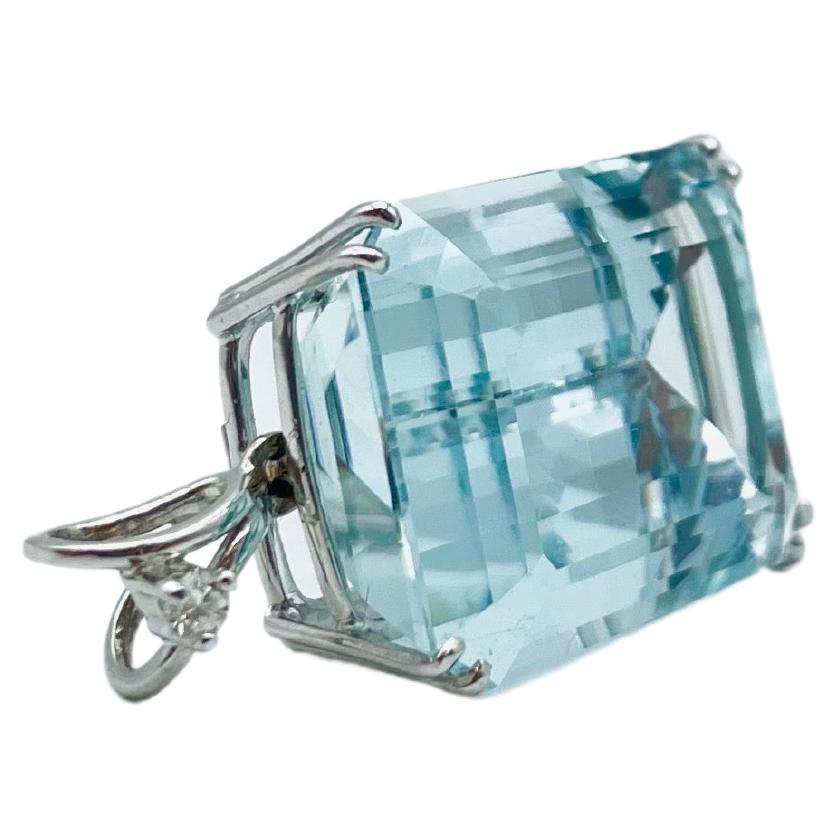 Behold a dreamlike pendant, a testament to exquisite craftsmanship, fashioned in 18-karat white gold. At its heart lies a splendid and remarkable Aquamarine gem, cut in the beguiling baguette style. This gemstone, measuring 1.6cm in width, 2.2cm in