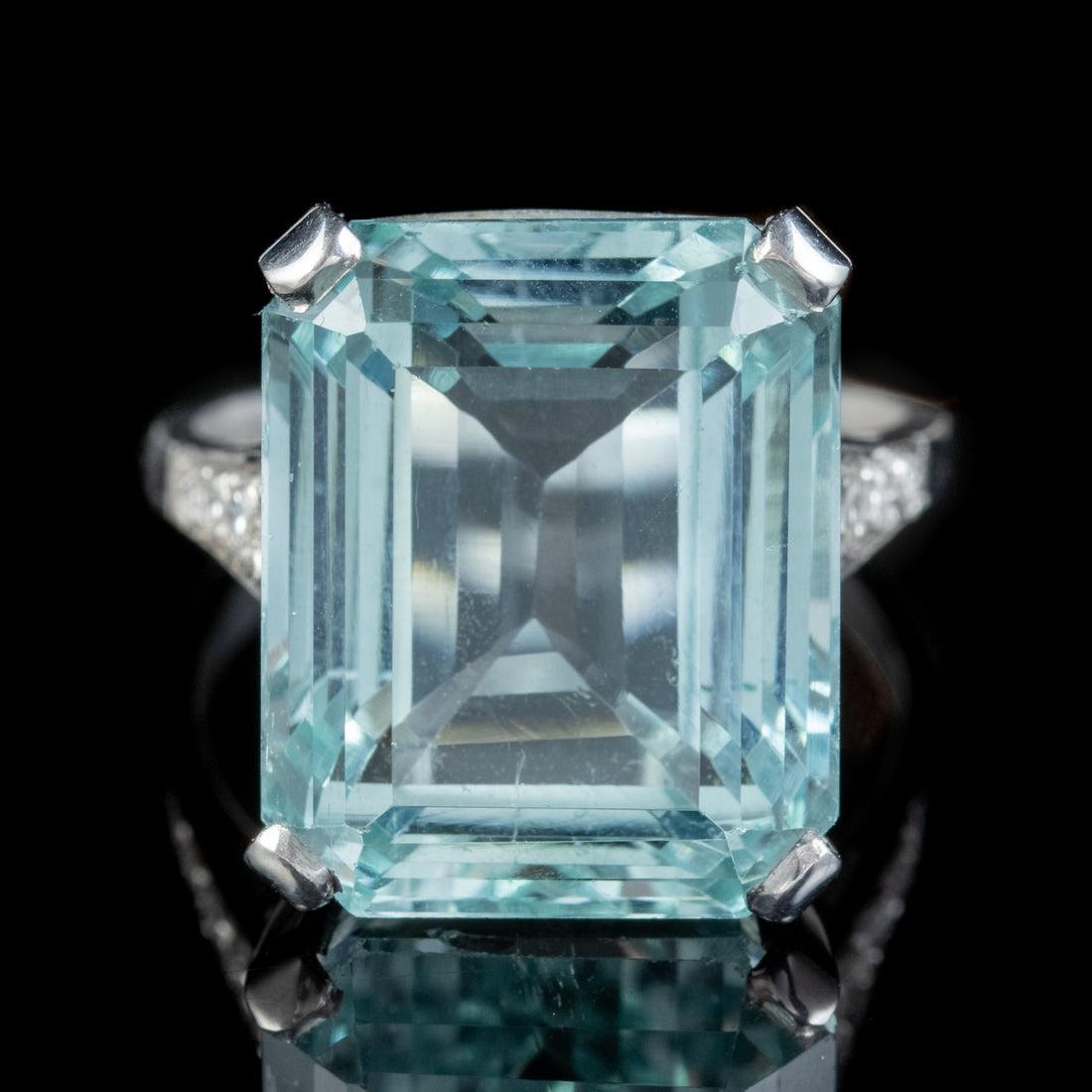 A magnificent Art Deco cocktail ring adorned with a beautiful emerald cut Aquamarine which weighs an impressive 18cts (approx.) and has a desirable clear ocean blue colour with flashes of green.

The shoulders are lined with bright Brilliant Cut