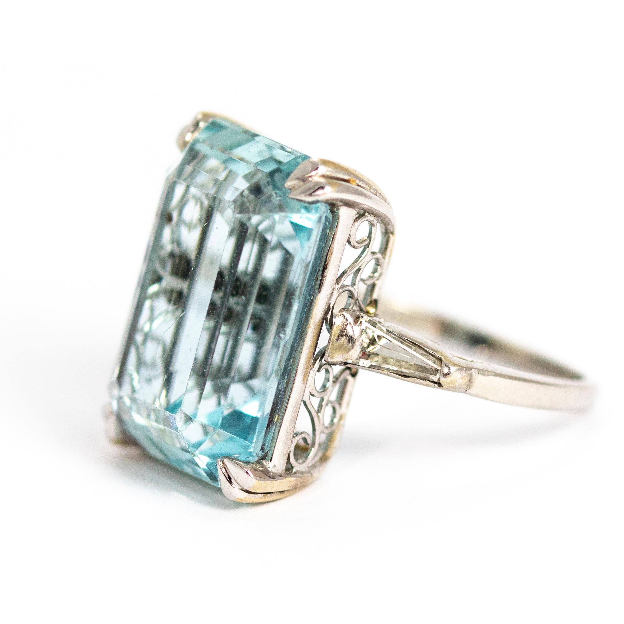 A spectacular Art Deco cocktail ring dating from circa 1910. The exquisite aquamarine measures 19.19mm by 13.98mm and has fantastic colour and depth, sitting in an elegant open gallery. Flanking the central stone are two glorious tapered