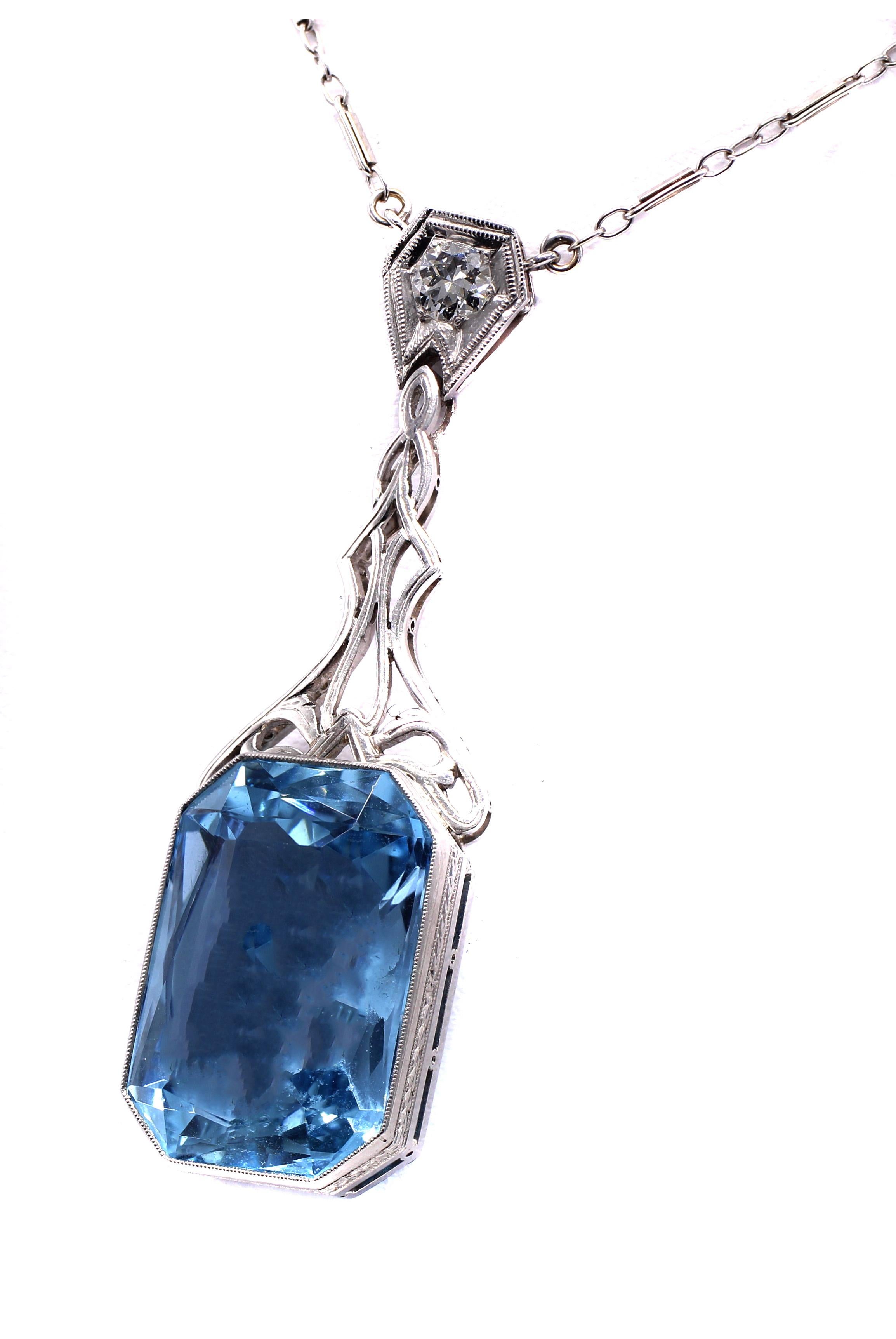 A gorgeous Santa Maria Blue rectangular step cut aquamarine is the centerpiece of this Art Deco pendant necklace. The perfectly cut, lively and sparkly aquamarine has been measured to weigh approximately 20 carats and is set in a bezel of platinum