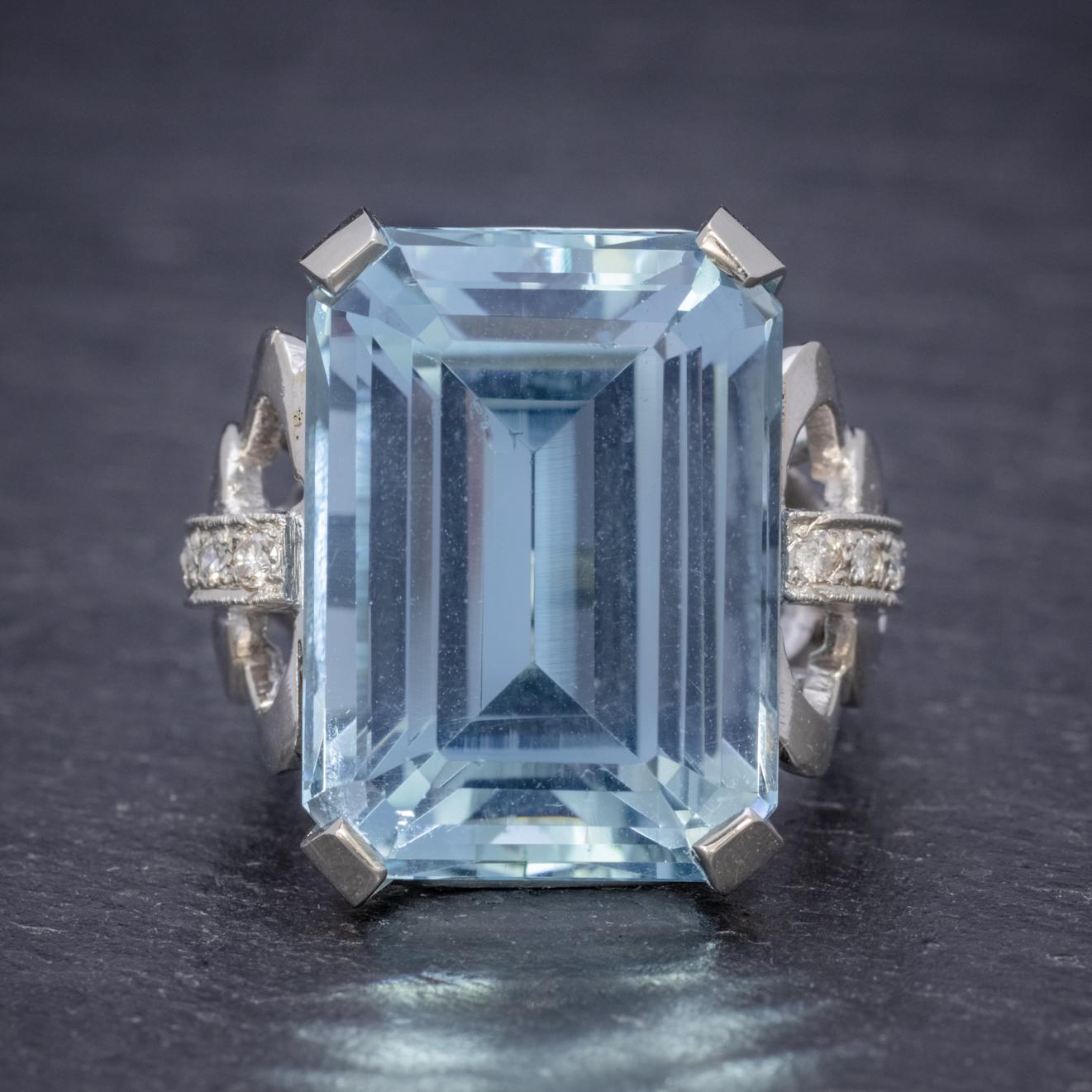 A magnificent Art Deco cocktail ring adorned with a breath-taking emerald cut Aquamarine which is approx. 35ct and a lovely clear ocean blue colour with flashes of inner green. 

The Aqua is claw set in a robust 14ct White Gold gallery with a fancy