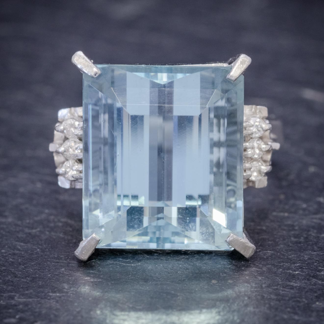 A magnificent Art Deco cocktail ring set with a breath-taking emerald cut Aquamarine which is a lovely clear ocean blue colour weighing 14.88ct and flanked with a row of three Diamonds down each side. 

The Diamonds are clean, bright SI 1 clarity –