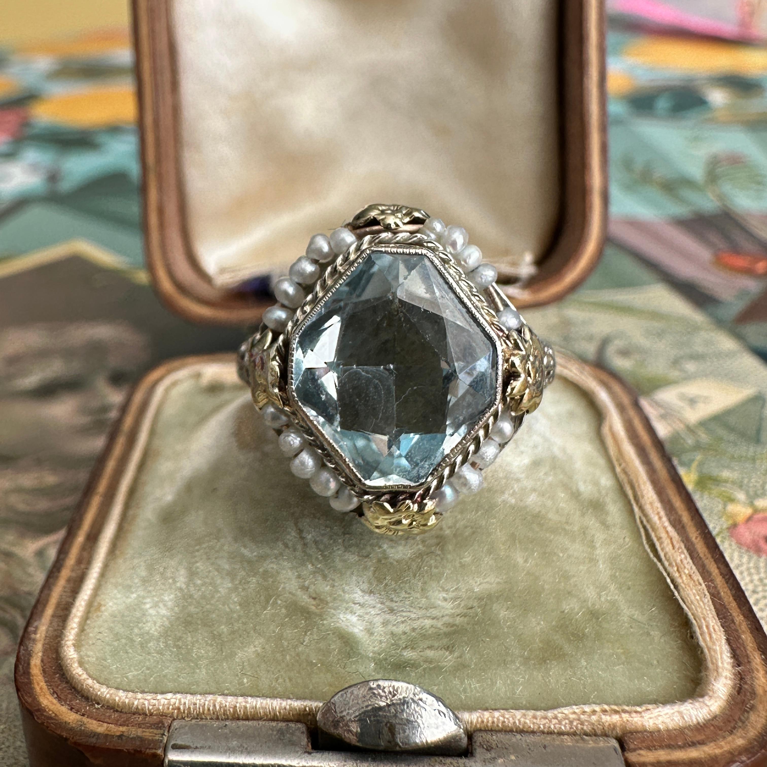 Details:
Stunning 14K white gold filigree, aquamarine ring—with seed pearls, flowers in yellow gold and white gold filigree! The aquamarine measures 11mm x 9.5mm, with a classic beautiful light blue color. The height of the aqua at the center of the