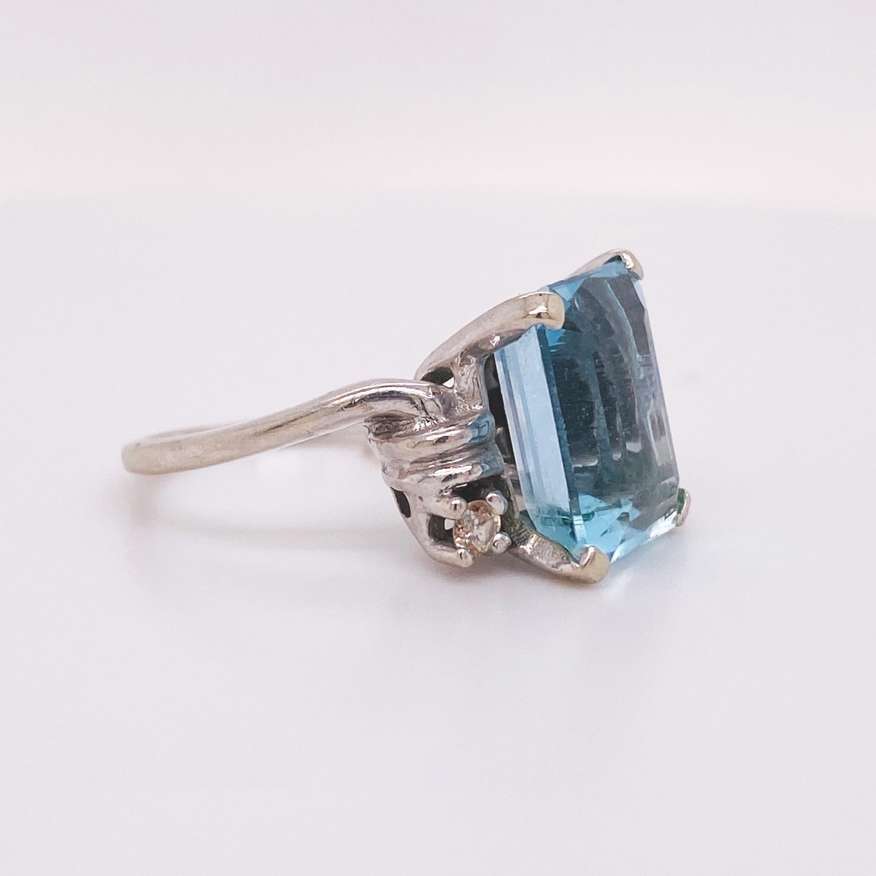 This is a fabulous Art Deco ring circa 1935. This classic emerald cut aquamarine ring has a gorgeous look accented on either side with genuine natural diamonds. The 14 karat white gold is a cool color metal that is gorgeous with the cool blue color
