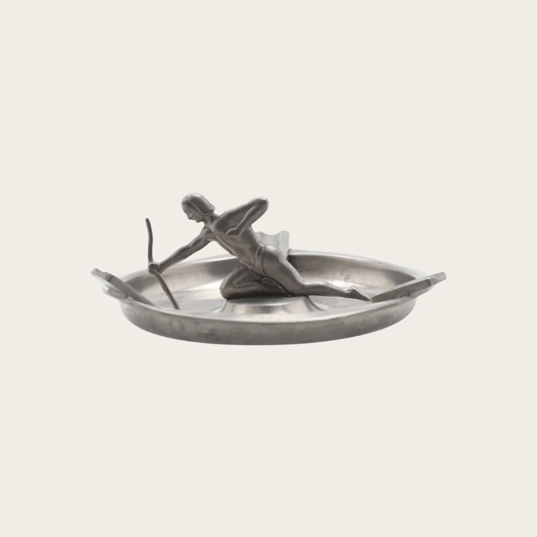 1930er Jahre, Schweden. Dieser Aschenbecher im Art-Déco-Stil verfügt über integrierte Zigarettenablagen und einen auffälligen, skulpturalen Bogen in der Mitte. Mit dem Svenskt Tenn-Stempel auf der Unterseite ist es von Svenska Metallverken (SvM)