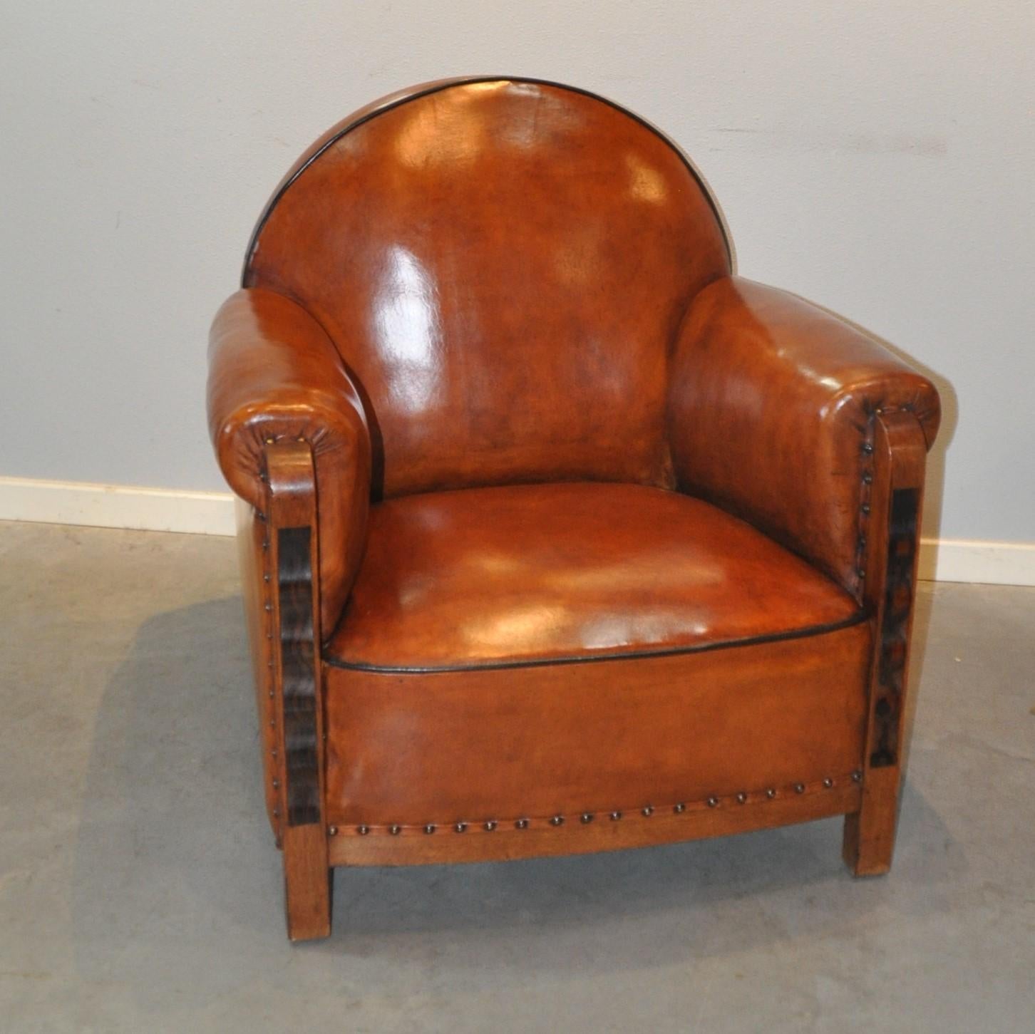 Beautiful Art Deco armchair with Coromandel elements. Reupholstered in first class sheep leather and finished all around with nails and black piping. The pillow is fixed. 
 