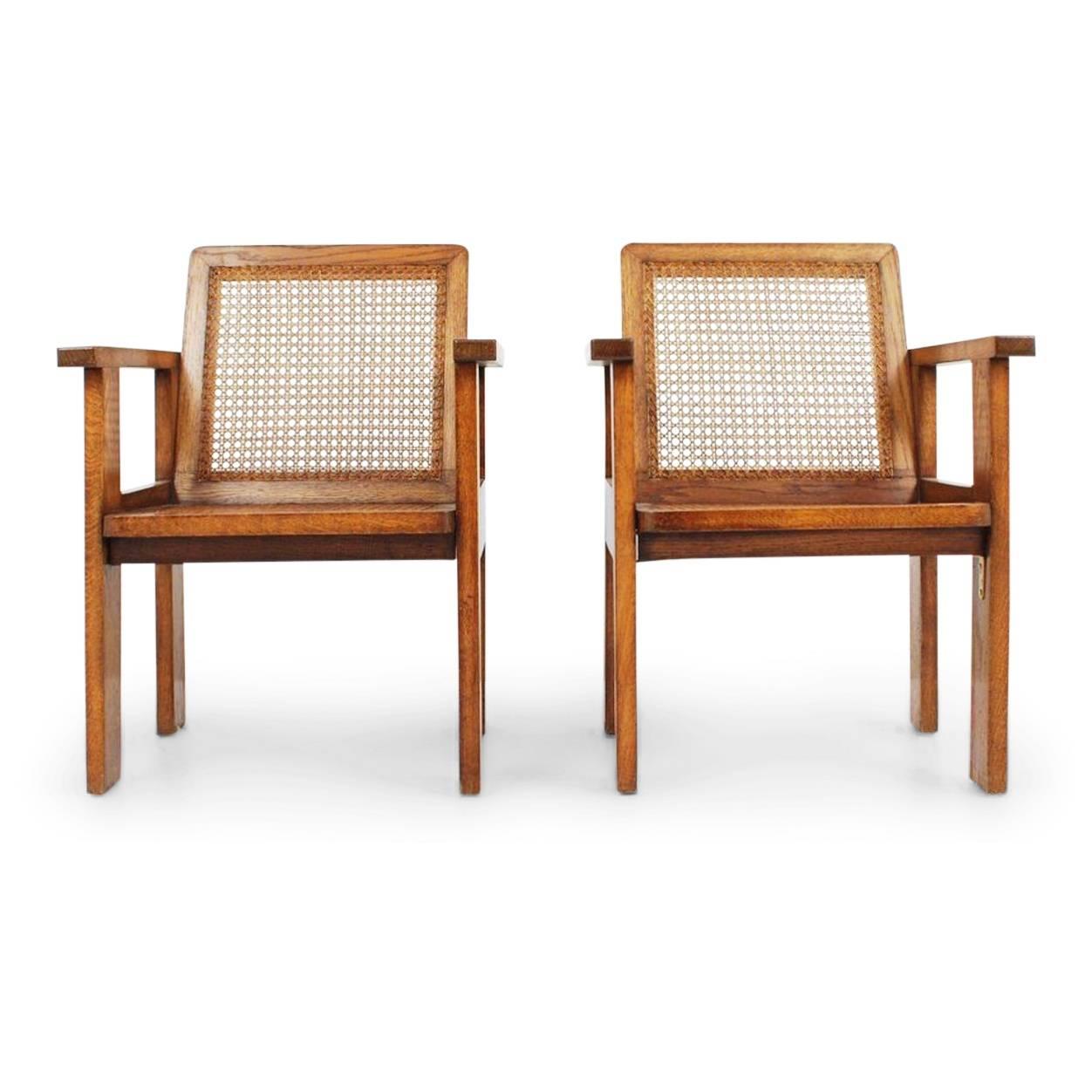 Pair of quarter sawn oak Art Deco armchairs with caned backs and seats, circa 1930. These sculptural club chairs feature the use of clean lines and minimal design making these handsome armchairs suitable for any space. 

The style of these chairs