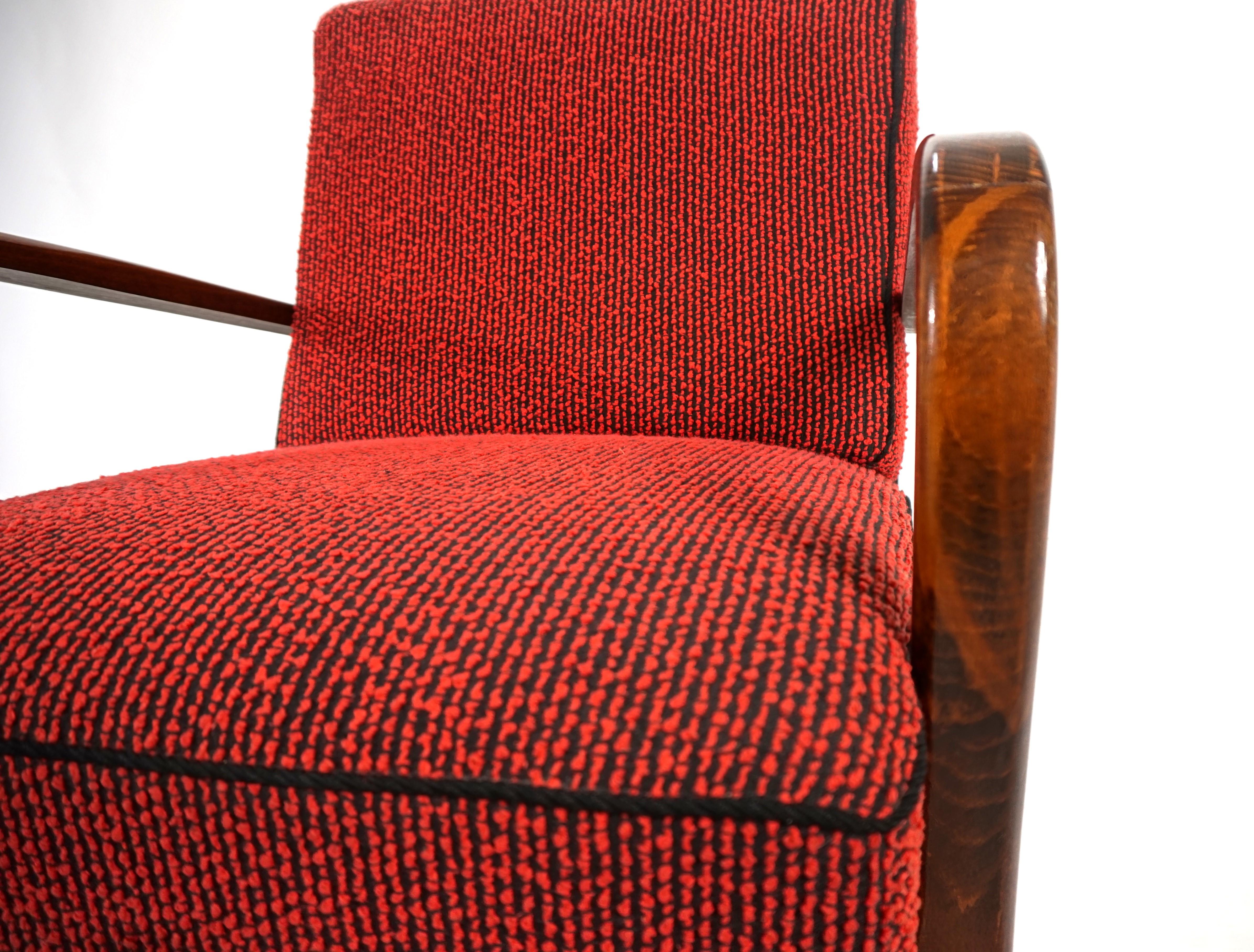 El sillón Art Déco viene con su tapicería original, que parece como nueva. El sillón lleva décadas en una habitación de invitados y nunca se ha utilizado. El tejido de lana roja, con una capa interior negra, está ribeteado con ribetes negros y es de
