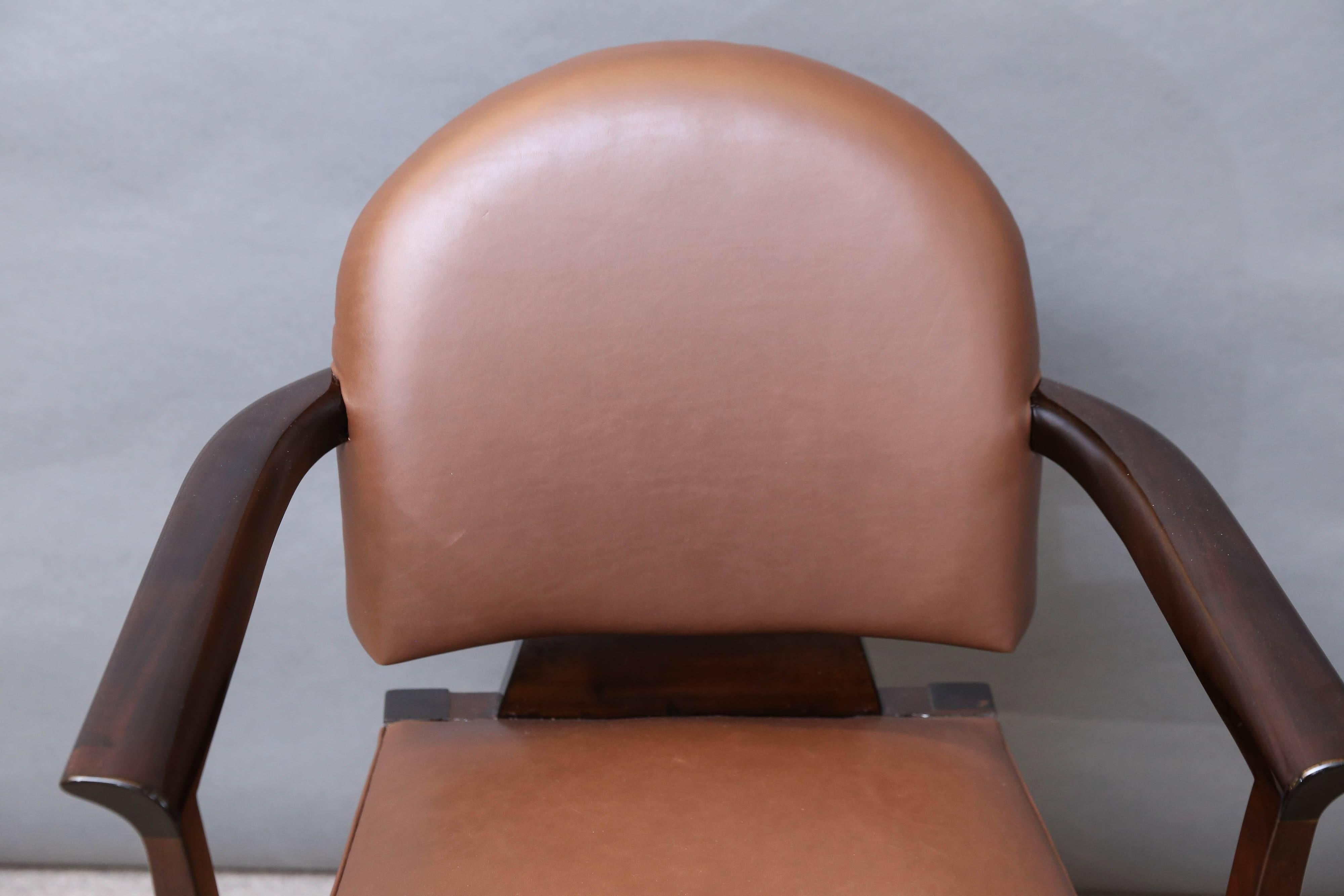 Body of the chair is made out of walnut wood. It has slick slightly curved outwards armrests. Back and sit parts are detached. They are newly re-upholstered in brown cowhide. The chair is elevated by four elongated legs. Two back legs are slightly