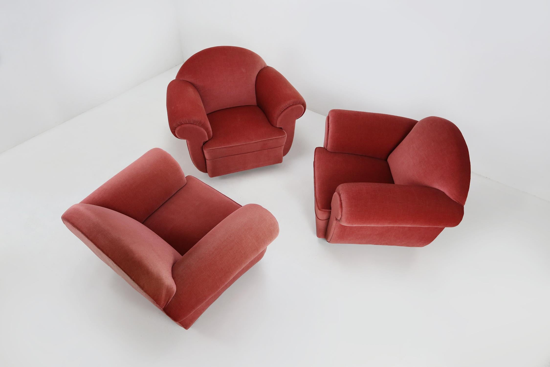 A set of Art Deco armchairs in a red salmon color velvet upholstery in a overall good condition. The rounded forms of the chairs are applying a dynamic accent to the design. Overall, this pair will make a great accent in one's Mid-Century Modern