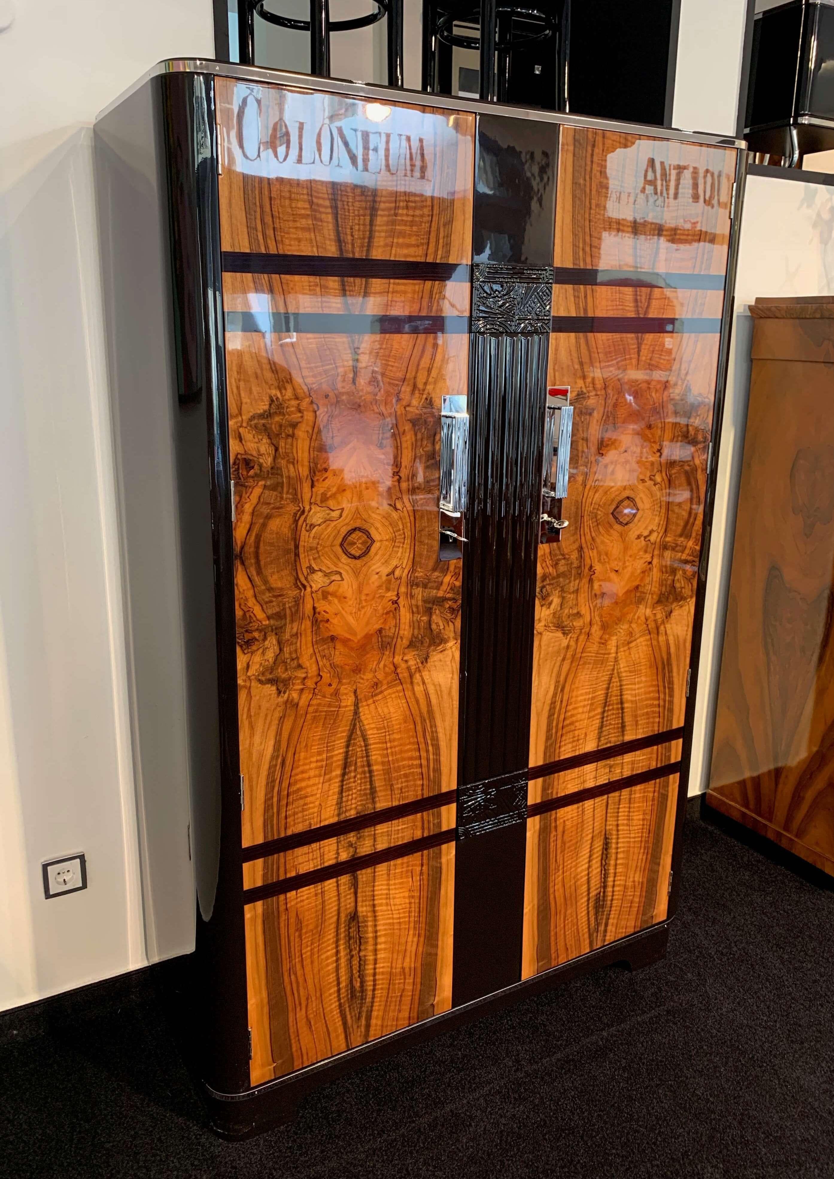 Wonderful Art Deco Wardrobe / Armoire / Dresser

Manufacturer: C.W.S. LTD. Cabinet Factory, London.
Nice Walnut Veneer and blackened Stripes Inlays at the front.
Great, elaborate Polyurethan Lacquer, high-gloss polished.
Sides and middle bar