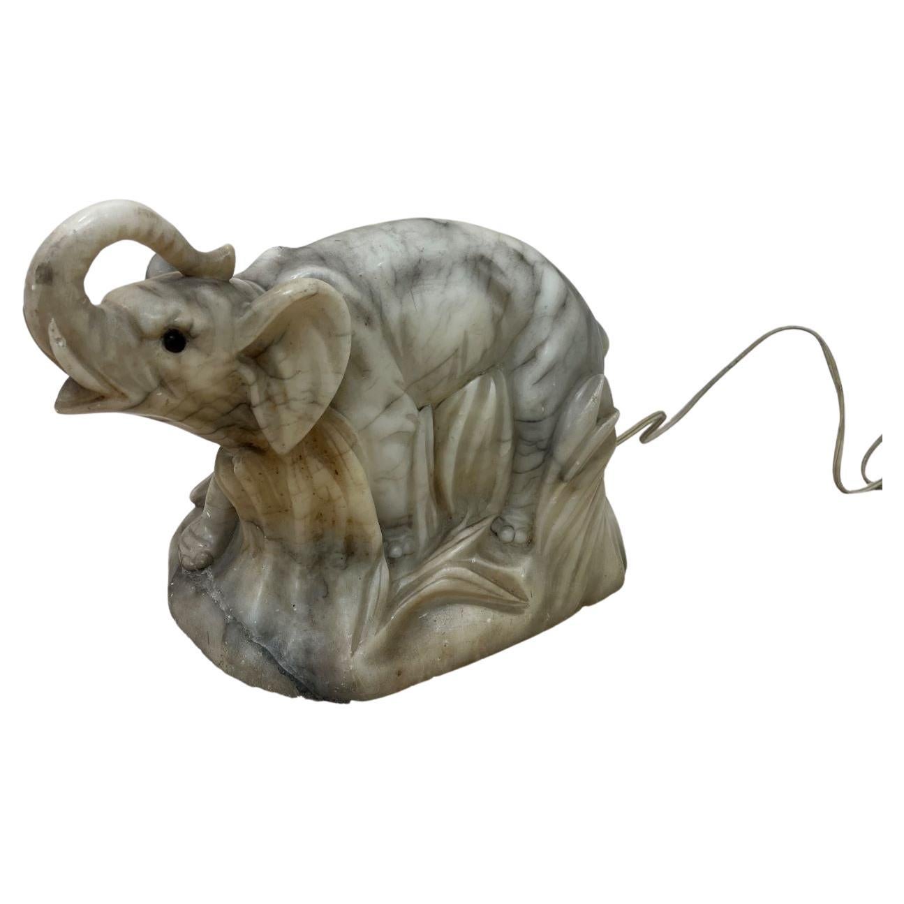  Lampe éléphant en albâtre sculpté Art Déco / Art Nouveau vers 1920-1930.  Lorsqu'elle est allumée, la lampe émet une belle lueur chaleureuse. Il présente une légère usure et des bords usés, et a peut-être été réparé au cours de sa vie. Cette