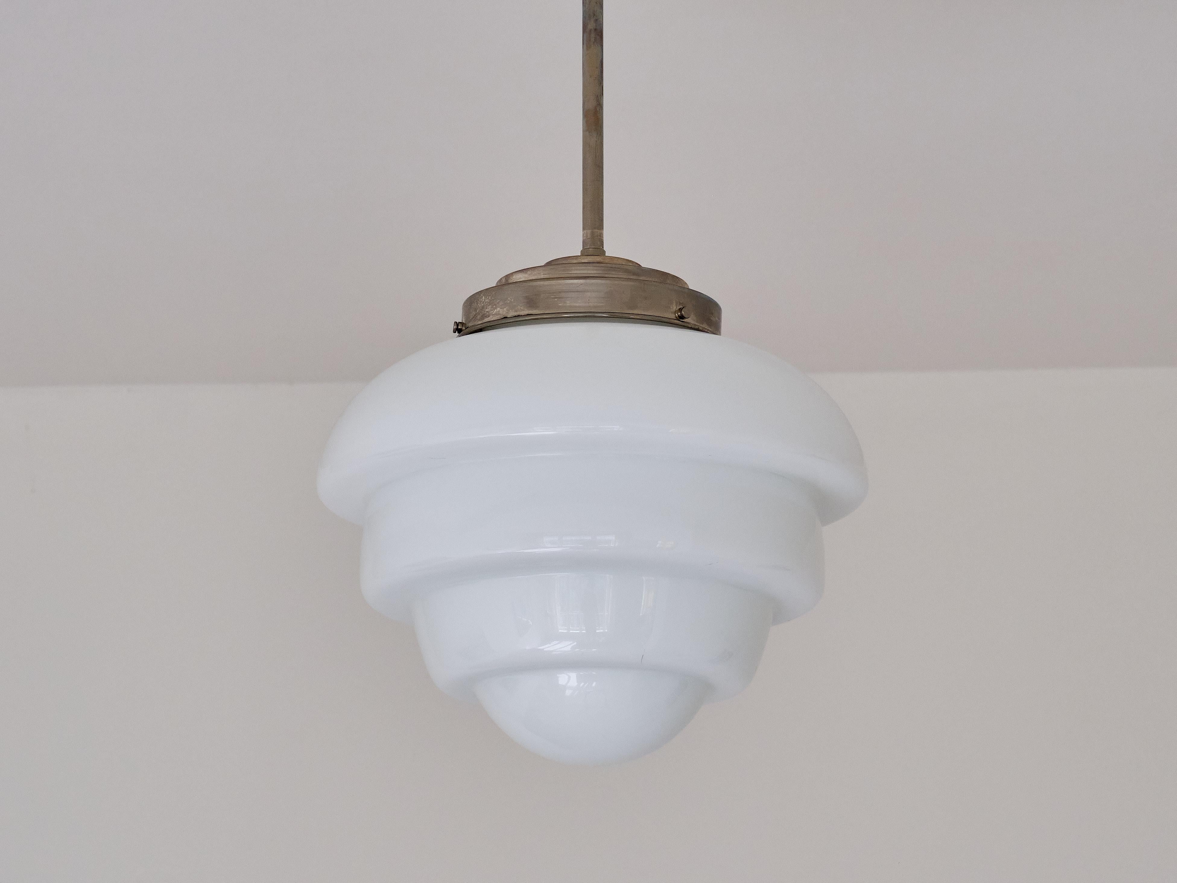 This rare pendant light was in The Netherlands in the 1930s. The striking shade is in a downwards muli-tiered artichoke shape. The shade is made of a slightly glossy, white opaline glass. The shade is attached to the fixture in nickel with a