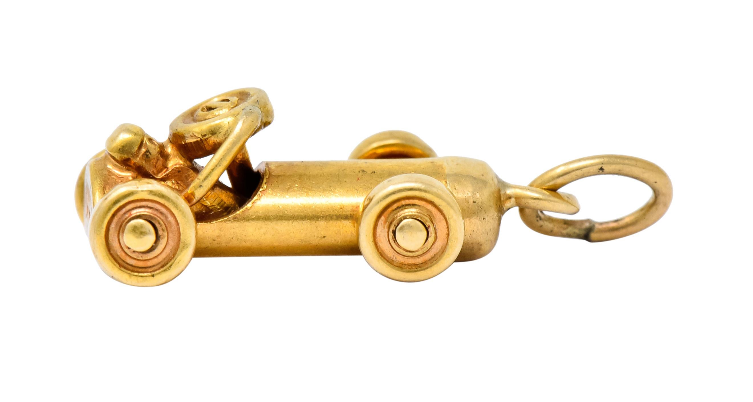 Charm designed as a classically streamlined soapbox derby car with a small reclining driver at the steering wheel

With articulated wheels and completed by a jump ring bale

Stamped 14K for 14 karat gold

Circa: 1930s

Measures: 3/8 x 3/4 inch