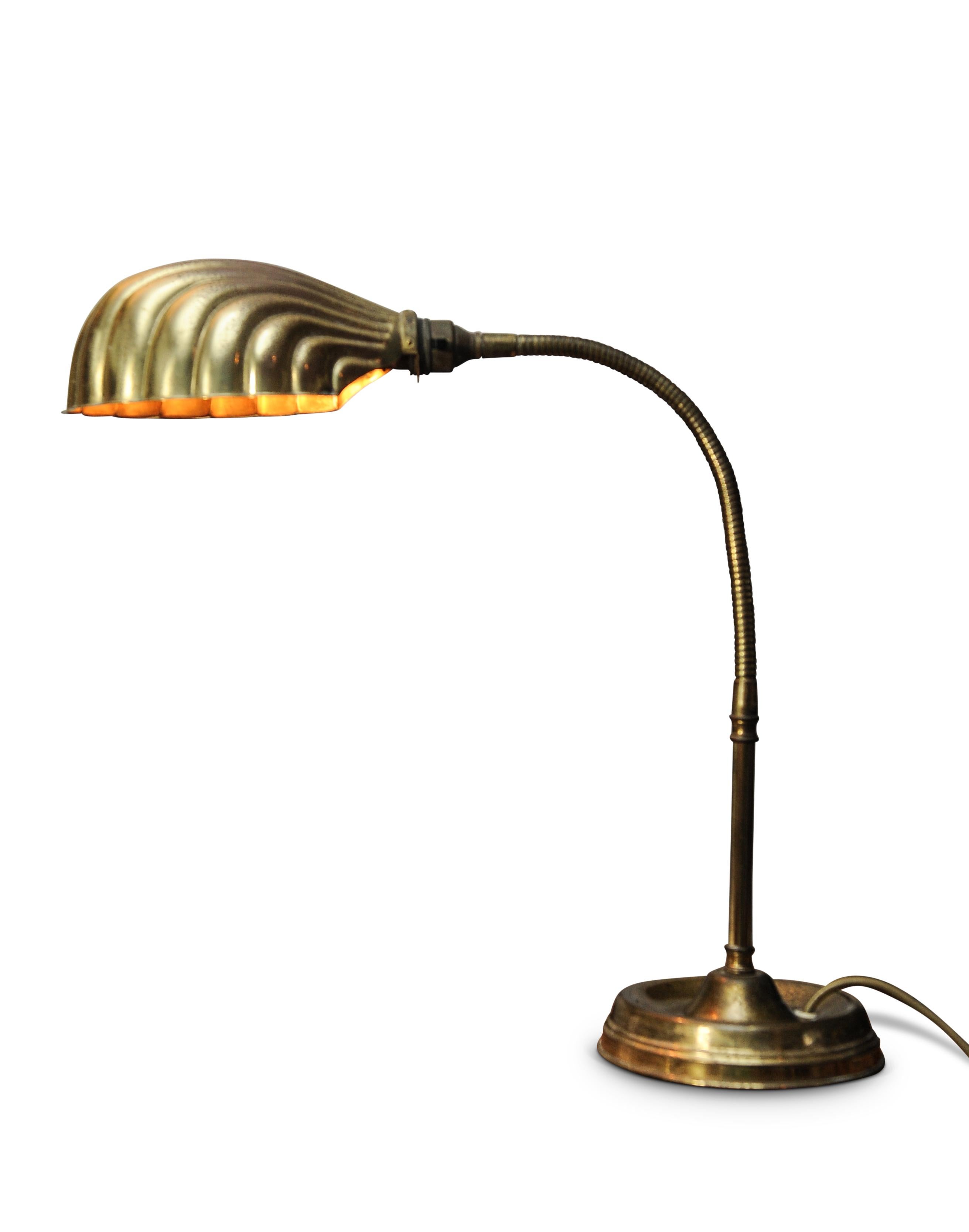 Early 20th century Art Deco articulated brass gooseneck desk lamp with decorated Brassed Copper Shell Shaped Shade on a circular vrass weighted base 1920s.