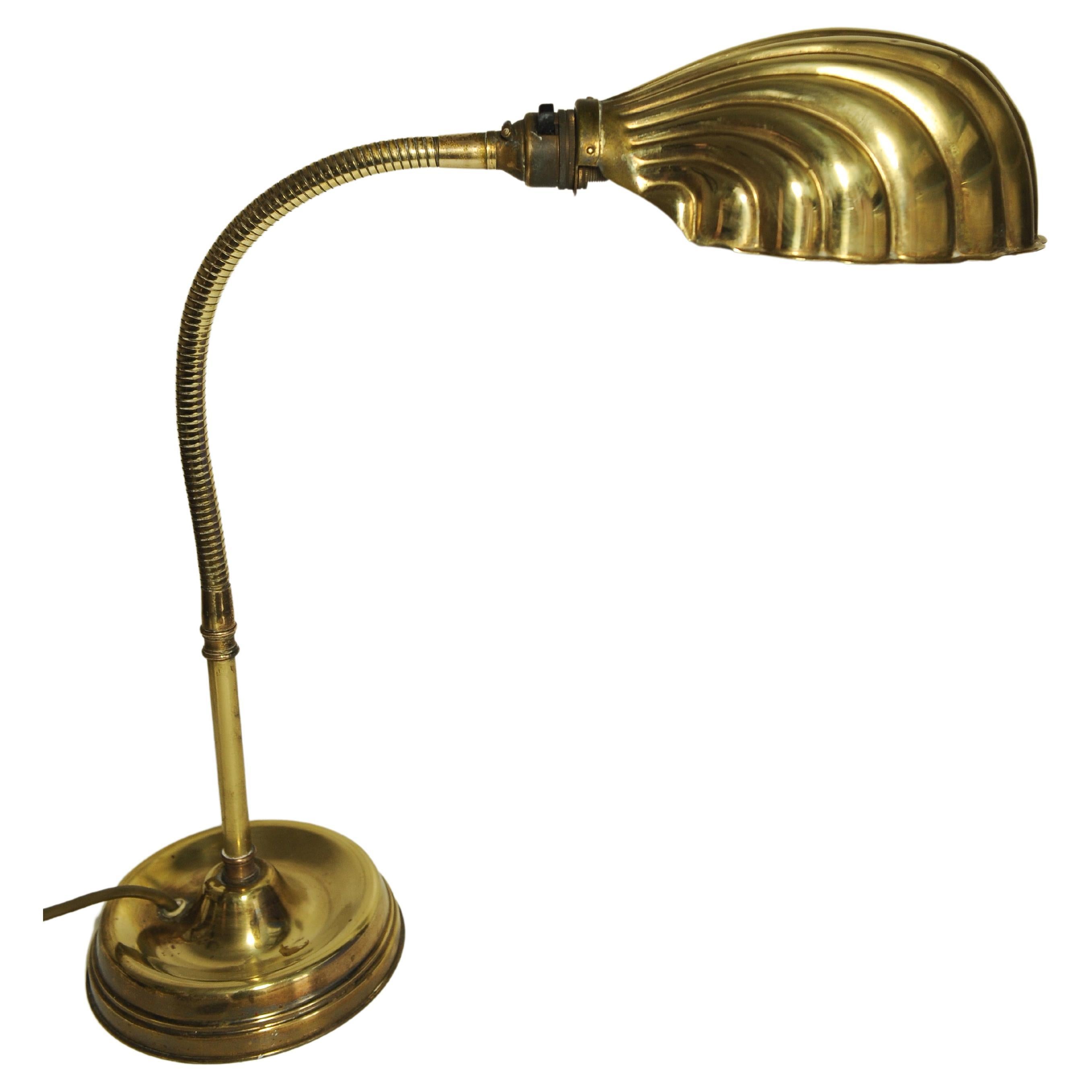 Early 20th century Art Deco articulated brass gooseneck desk lamp with decorated Brassed Copper Shell Shaped Shade on a circular brass weighted base 1920s.