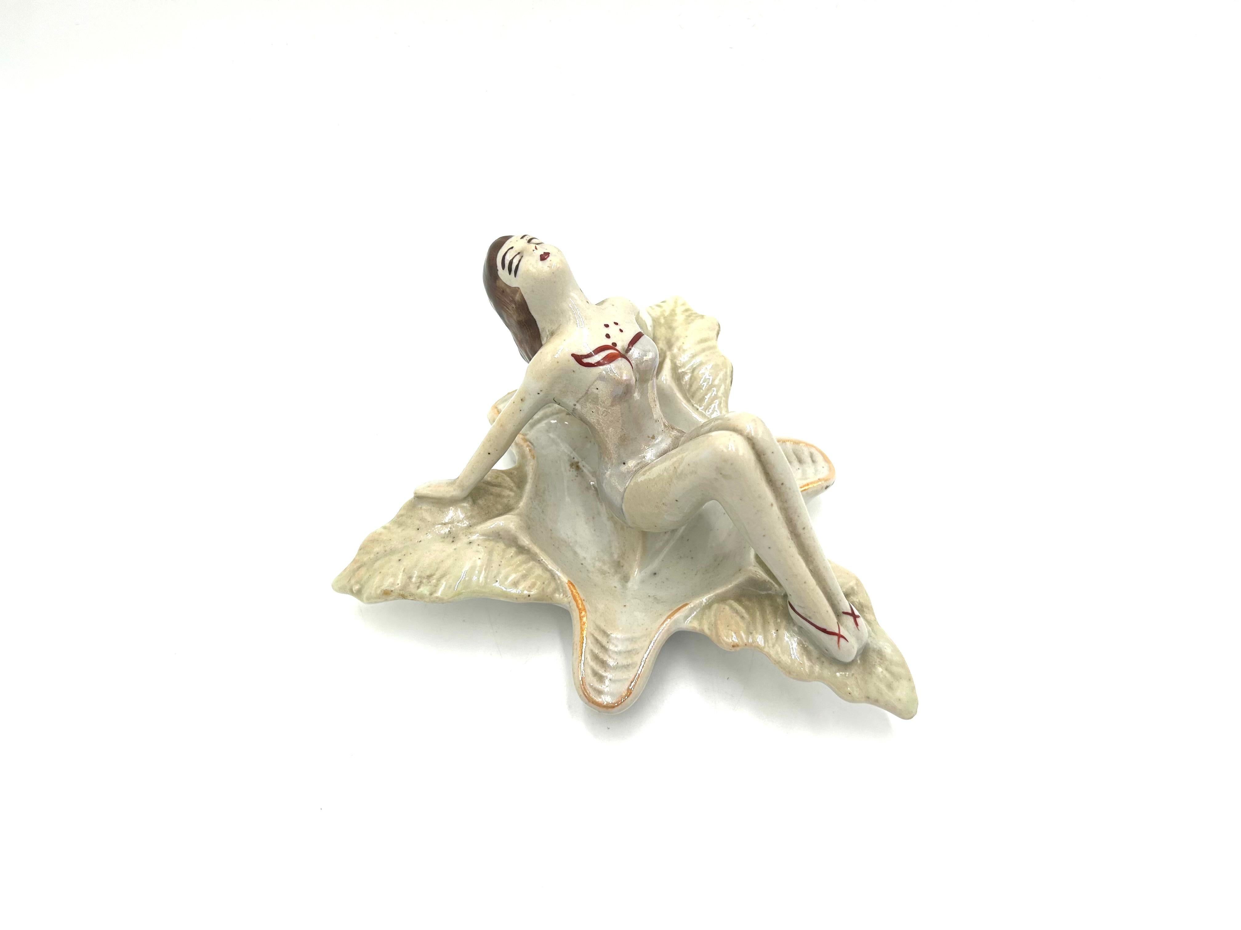 Der ikonische Aschenbecher in Form einer Frau im Badeanzug, die auf einem Blatt sitzt. Entworfen von Zygmunt Buksowicz für die Steatyt-Fabrik in Kattowitz.

Sehr guter Zustand, keine Schäden

Höhe 10cm Breite 17x17cm