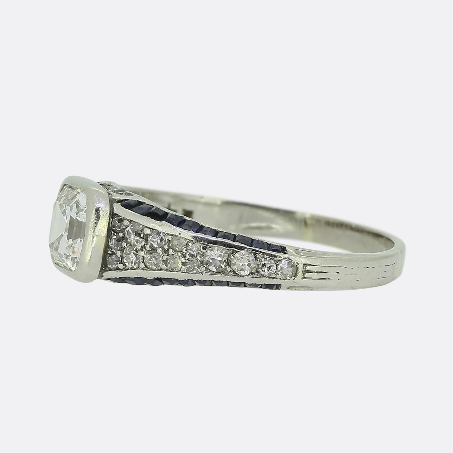 Il s'agit d'une bague très travaillée, datant de l'époque où le style Art déco était à la pointe du design mondial. En son centre se trouve un diamant de taille asscher, d'un blanc immaculé, solidement enchâssé dans une monture élégante. Les épaules