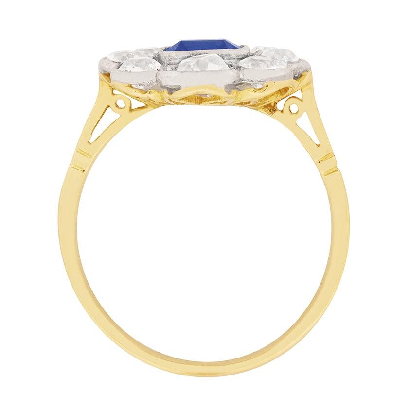 A one carat asscher cut sapphire is wrapped within a twinkling 1.90 carat, grain set border of old cut diamonds at the heart of this circa 1920s halo ring.

These antique jewels are hand-set in millegrained platinum atop an 18 carat yellow gold