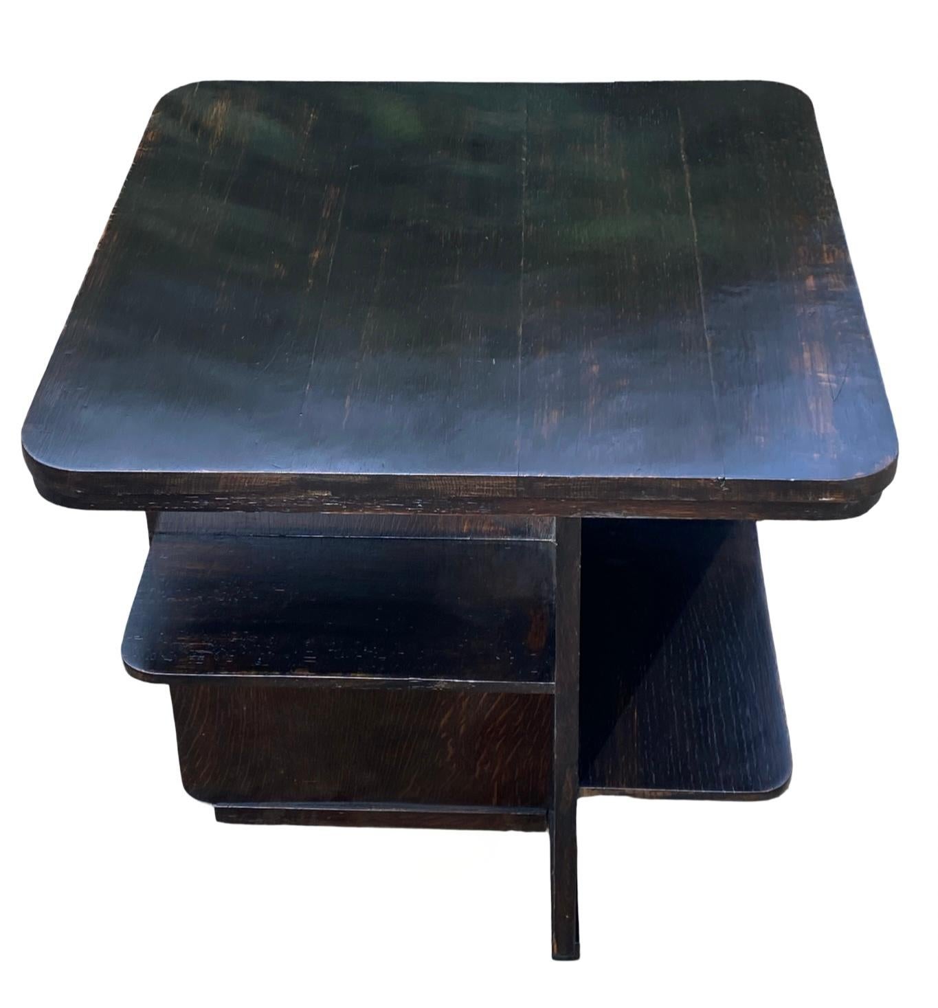 Siamo lieti di offrire questo grazioso tavolino da caffè Art Déco in rovere scuro con una piacevole patina sul piano che è sia asimmetrico che a spalle rotonde. Il piano superiore è dotato di ripiani perfetti per riporre i libri, il che lo rende