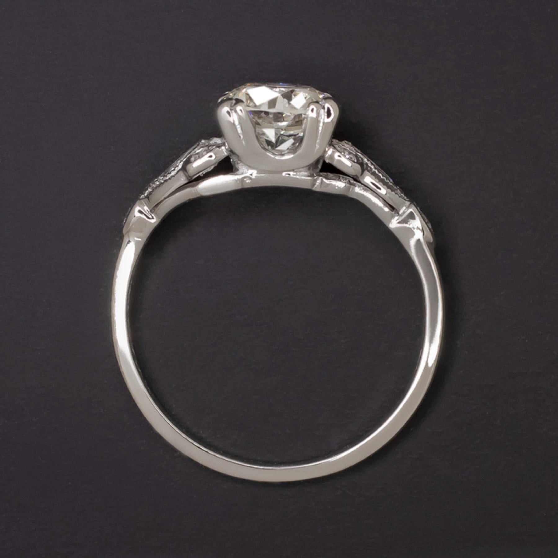 Art Deco engagement ring features a fiery 0.88ct old European cut diamond complemented by a glittering, diamond studded platinum setting. Beautifully white and completely eye clean, the center diamond has a vibrant look and an eye catching presence.