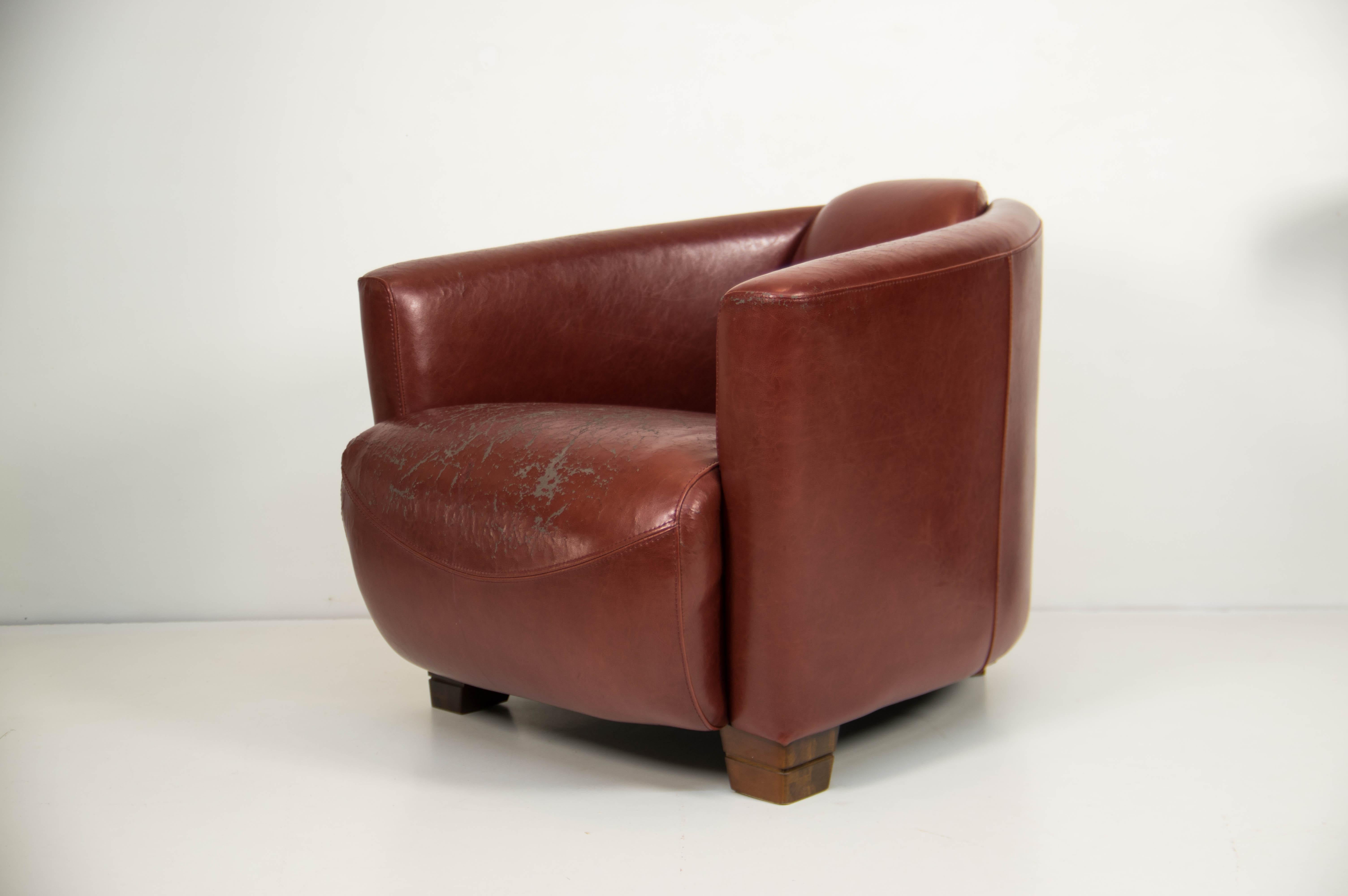 Ce fauteuil club en similicuir présente un revêtement rouge bordeaux magnifiquement vieilli avec une riche patine, ajoutant du caractère et de l'authenticité à tout espace de vie. Parfaite comme pièce d'appoint dans un salon, un bureau ou un coin