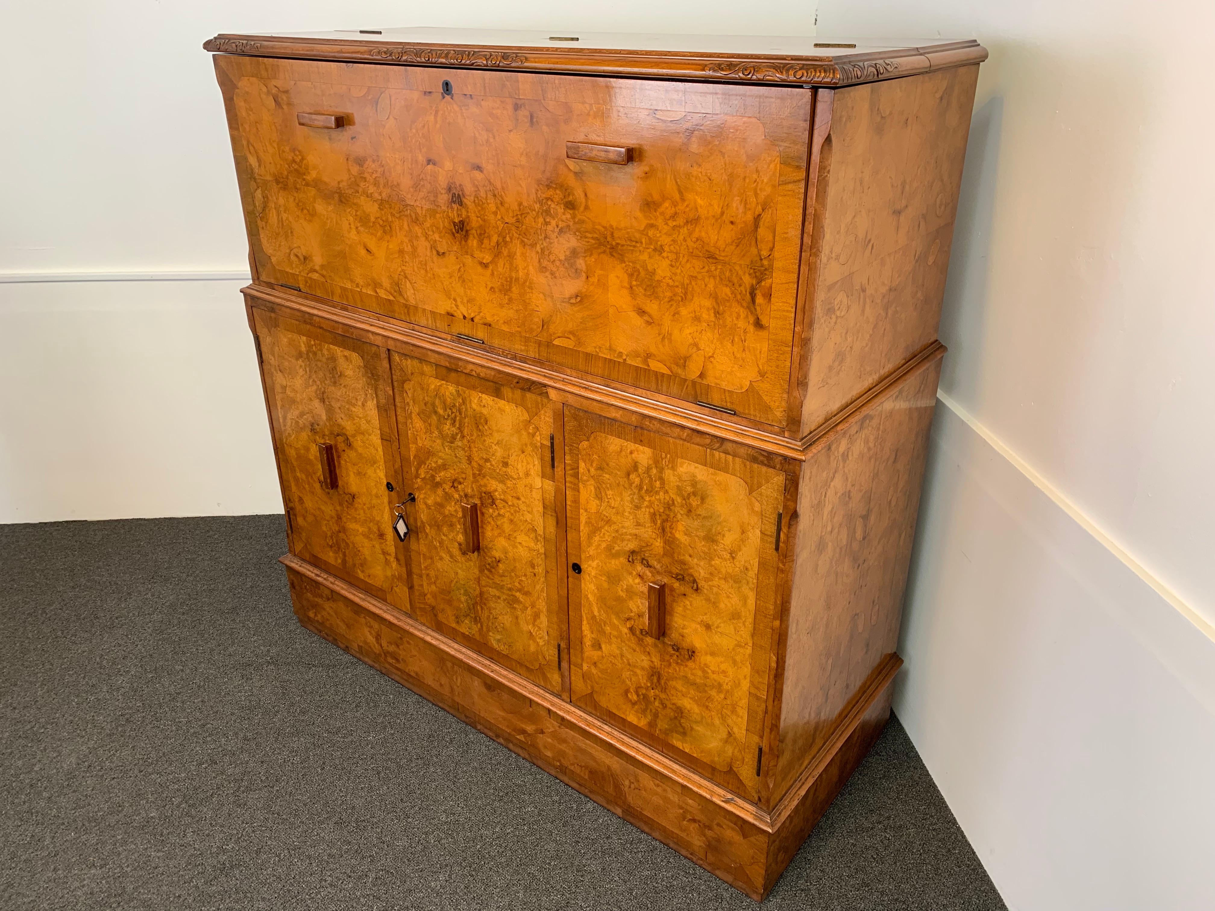 An attractive, elegant shaped Art Deco walnut cocktail cabinet. As the top is opened the light automatically comes on and the shelf automatically comes forward, to display a mirrored, birch and walnut interior. Perfect for setting of and storing