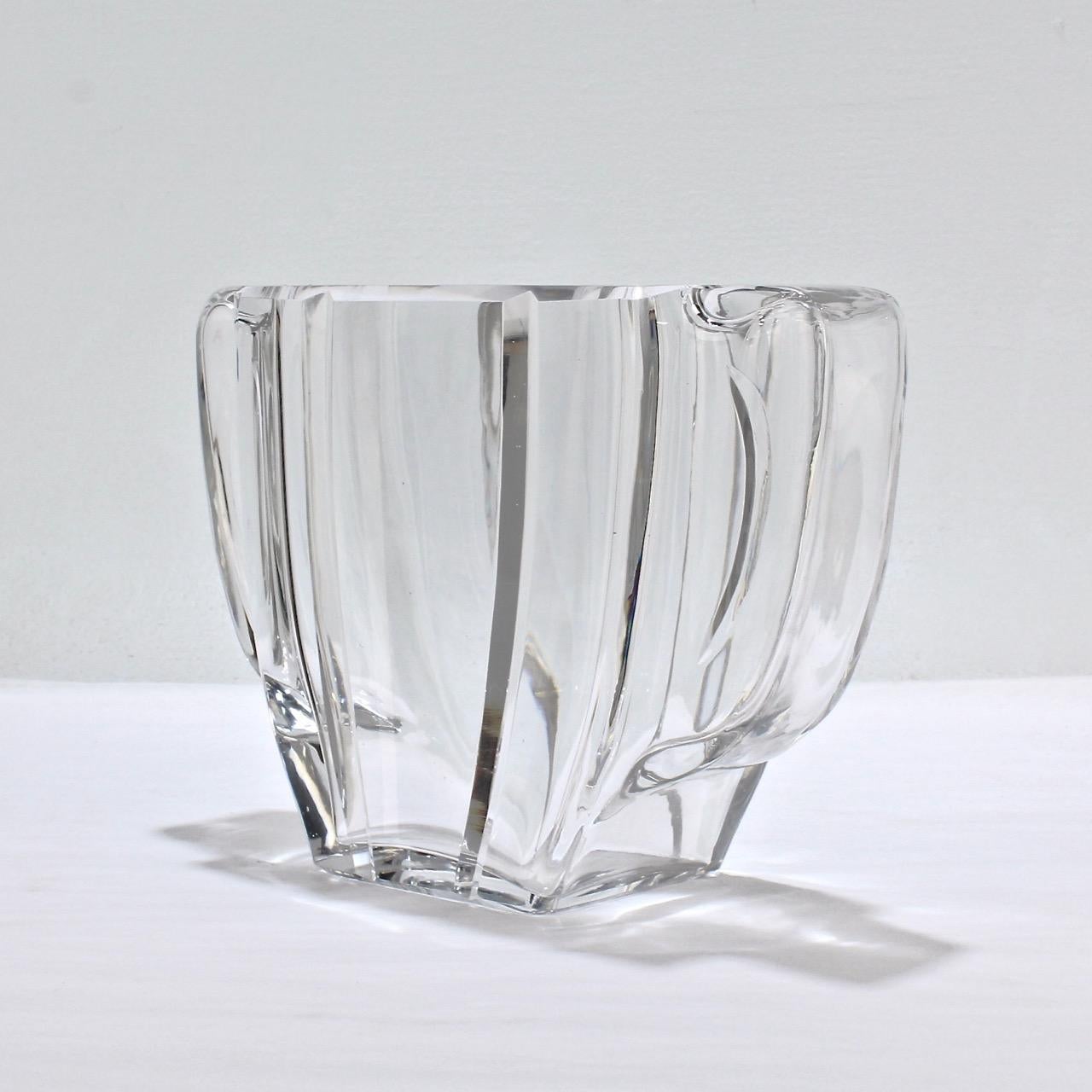 A hard-to-find Baccarat two-handled Art Deco vase.

Of slender form with hollow integral handles to each side. 

The base bears acid-etched Baccarat factory mark.

Measures: Height: ca. 5 3/4 in
Width: ca. 8 1/8 in.



 