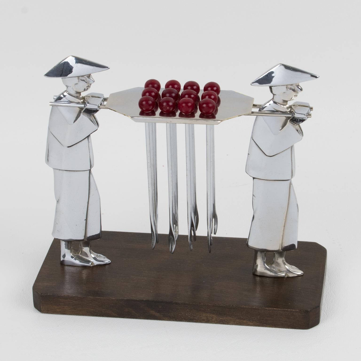 This lovely barware bar set cocktail picks features a carved chromed metal set of two carriers with a central holder. Twelve metal cocktail forks with red Bakelite bead finial are resting on the holder. The base is in varnish wood. This set has
