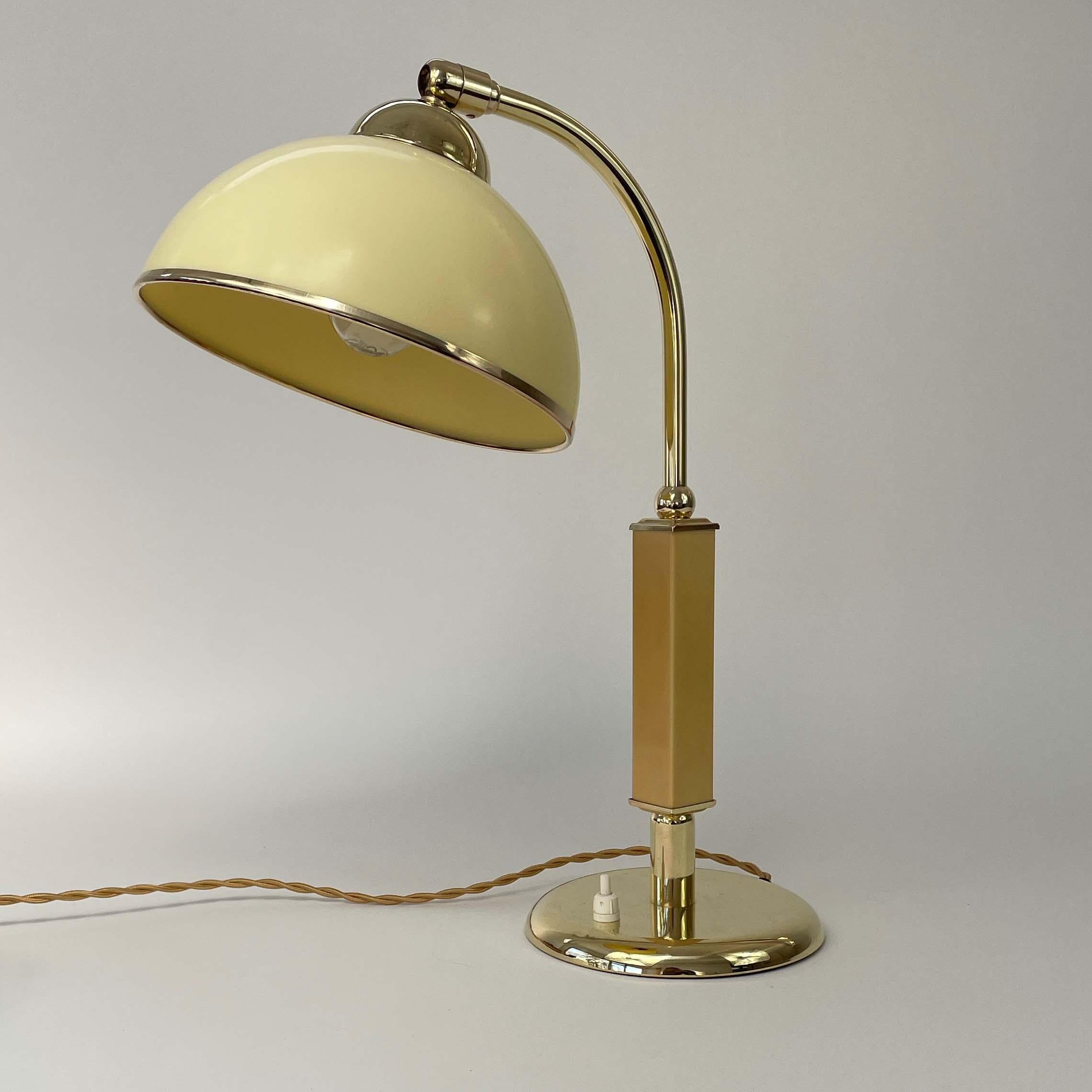 This unusual vintage table light was designed and manufactured in Germany in the 1930s during the Bauhaus period. It features a dome shaped dark cream colored bakelite lampshade, caramel / butterscotch colored lamp arm holder and brass hardware. The