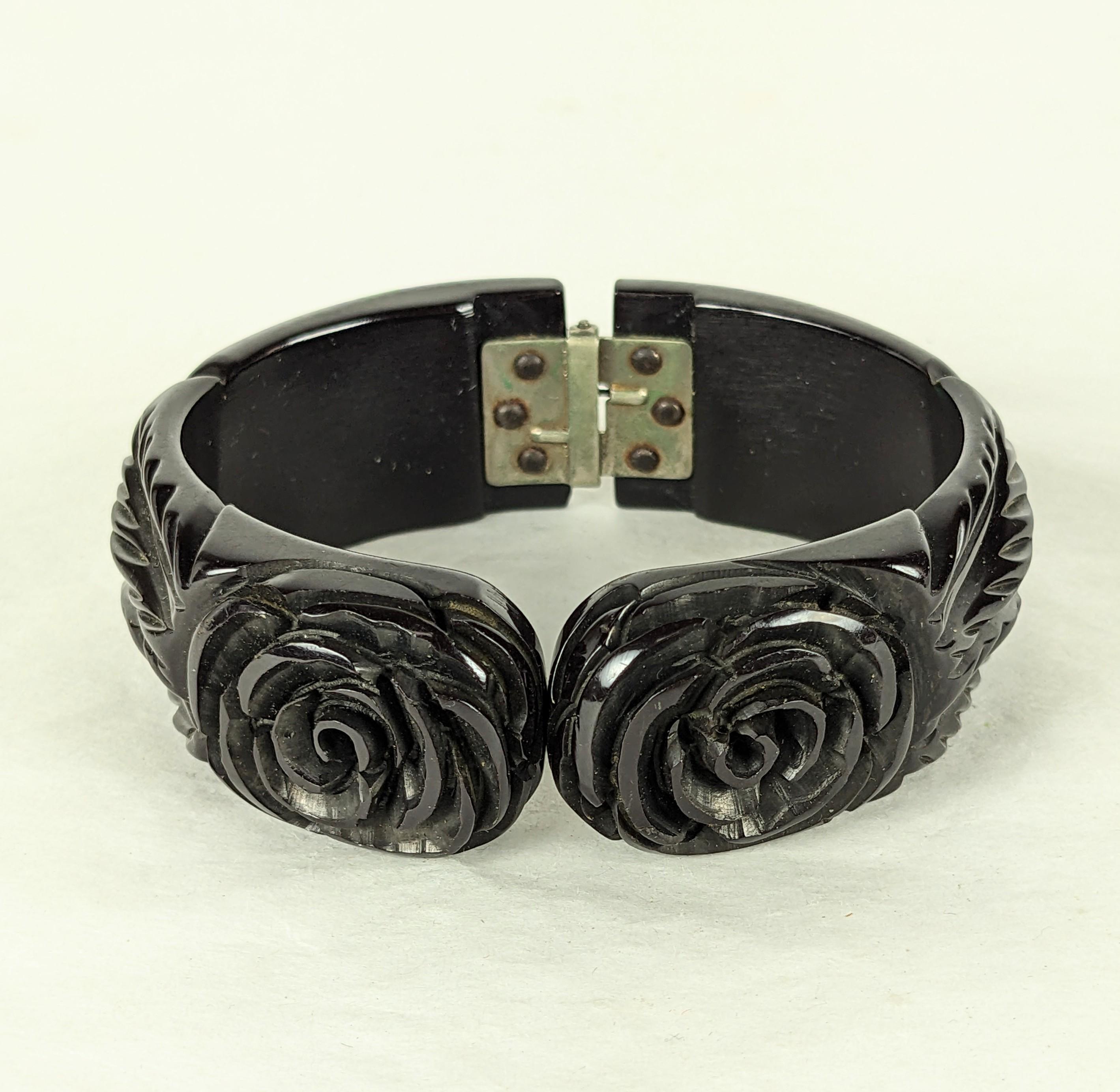 Art Deco Bakelit geschnitzt Rose Clamper Armband aus den 1920er Jahren. Handgeschnitztes schwarzes Bakelit mit 2 Blumenmotiven auf der Oberseite und geschnitzten Blättern an den Schultern. Das Scharnier auf der Rückseite ermöglicht den Zugang. 
1