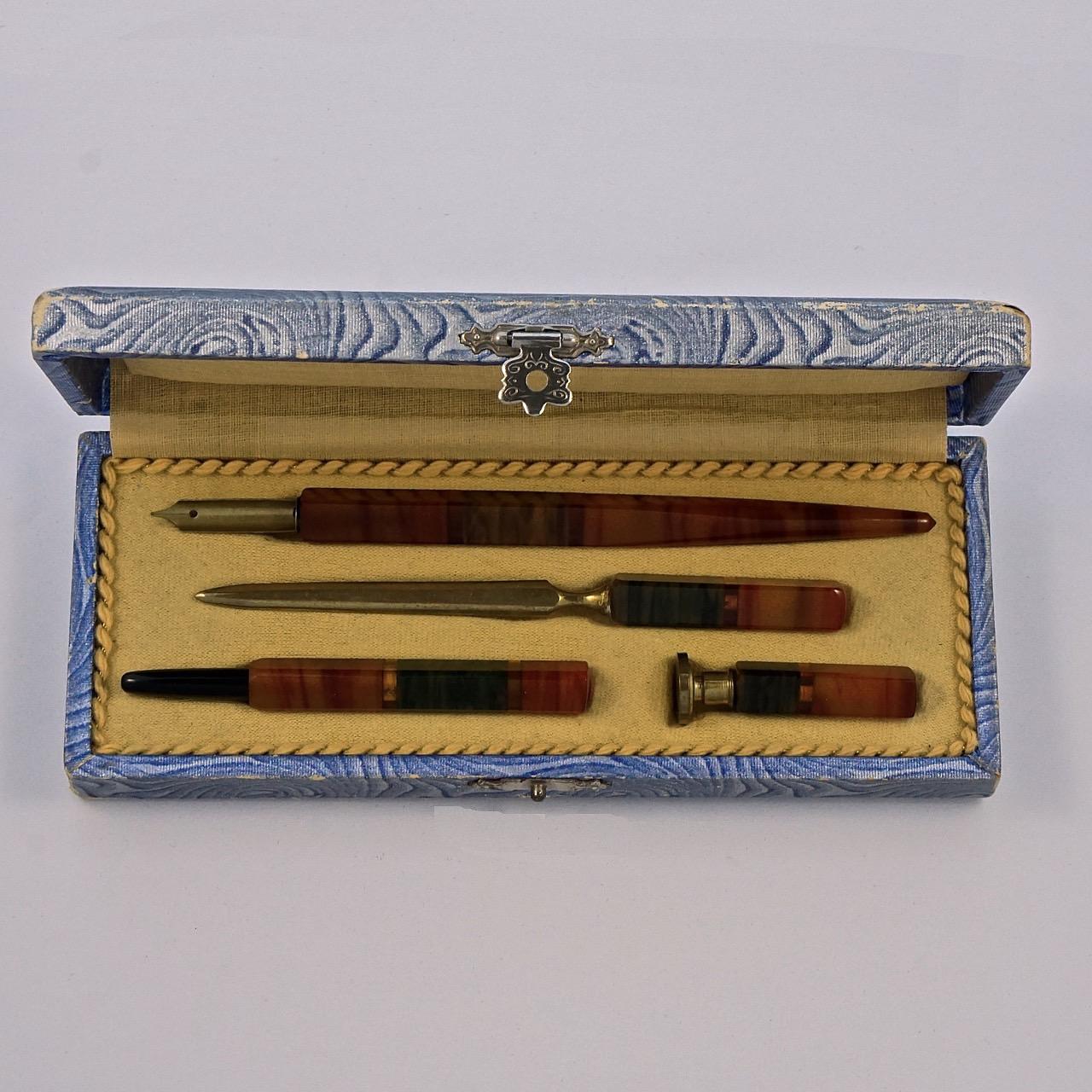 Beautiful Art Deco bakelite desk set in the original box, with an ink pen, revolving pencil with lead, letter opener and seal. The nib is stamped Geo W Hughes, Football, No. 1325, Breadth 5. The set is in very good condition, the blue box is