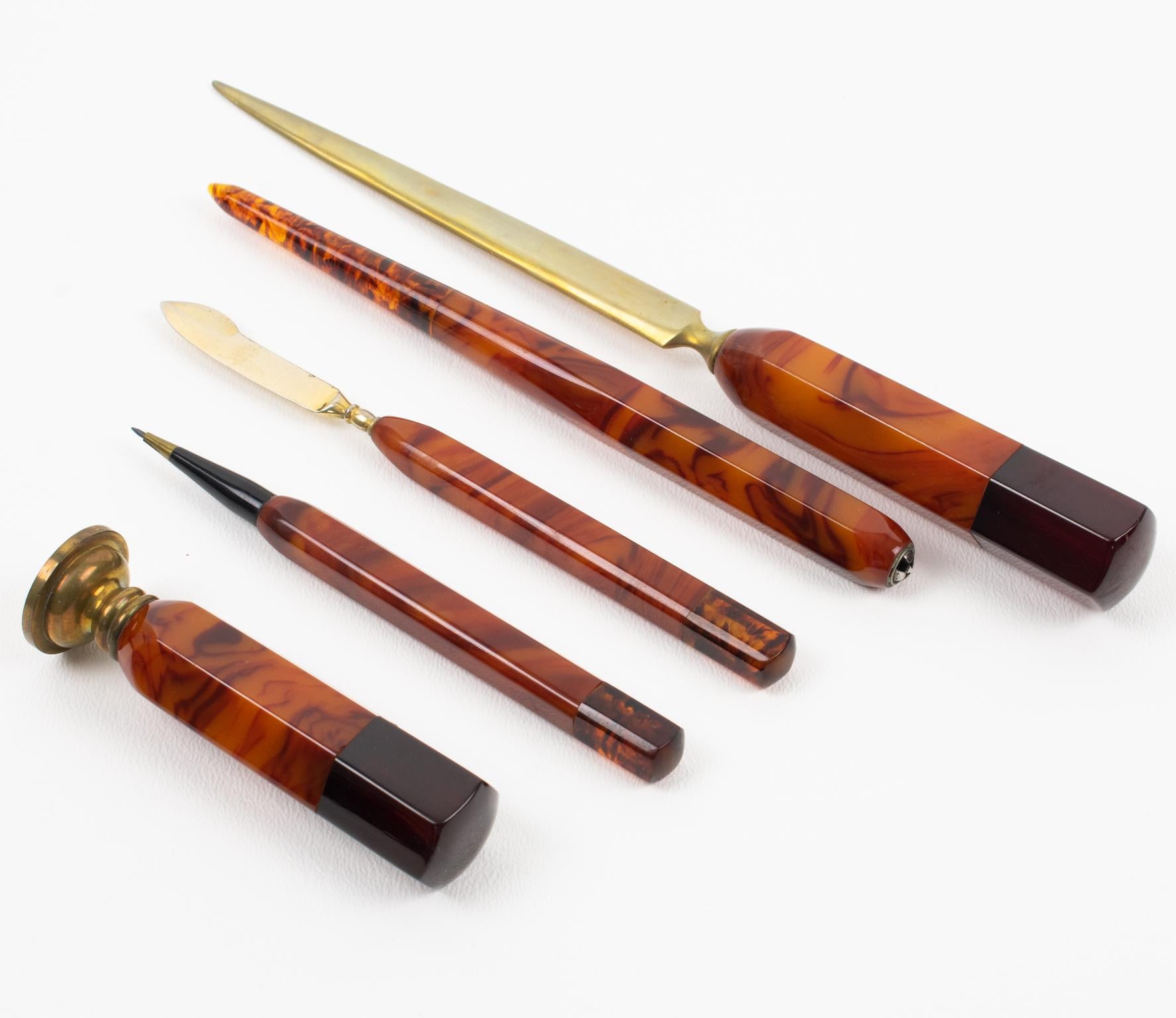 This stunning Art Deco Bakelite desk accessories writing set dates from the 1930s. The set is built of five pieces in its original box: a letter opener, paper cutter, pen holder, mechanical pencil, and wax stamp. Each piece is ornate with beautiful