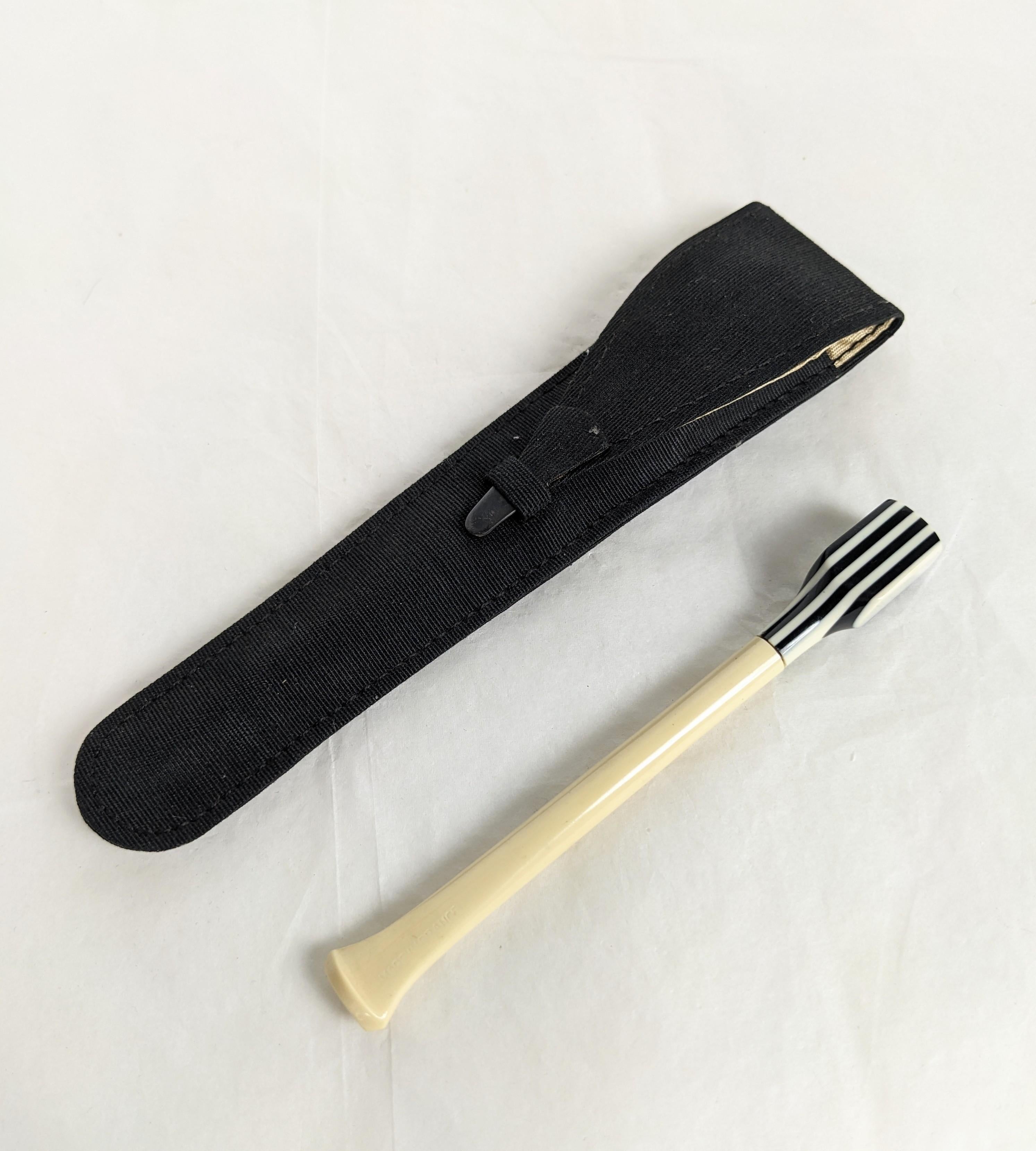 Porte-cigarettes Art Déco en bakélite stratifiée avec étui. Bakélite crème et noire laminée en bandes graphiques dans son propre étui en faille de soie noire doublé de soie ivoire. Fermoir à pointe en argent sterling. Ne semble pas avoir été
