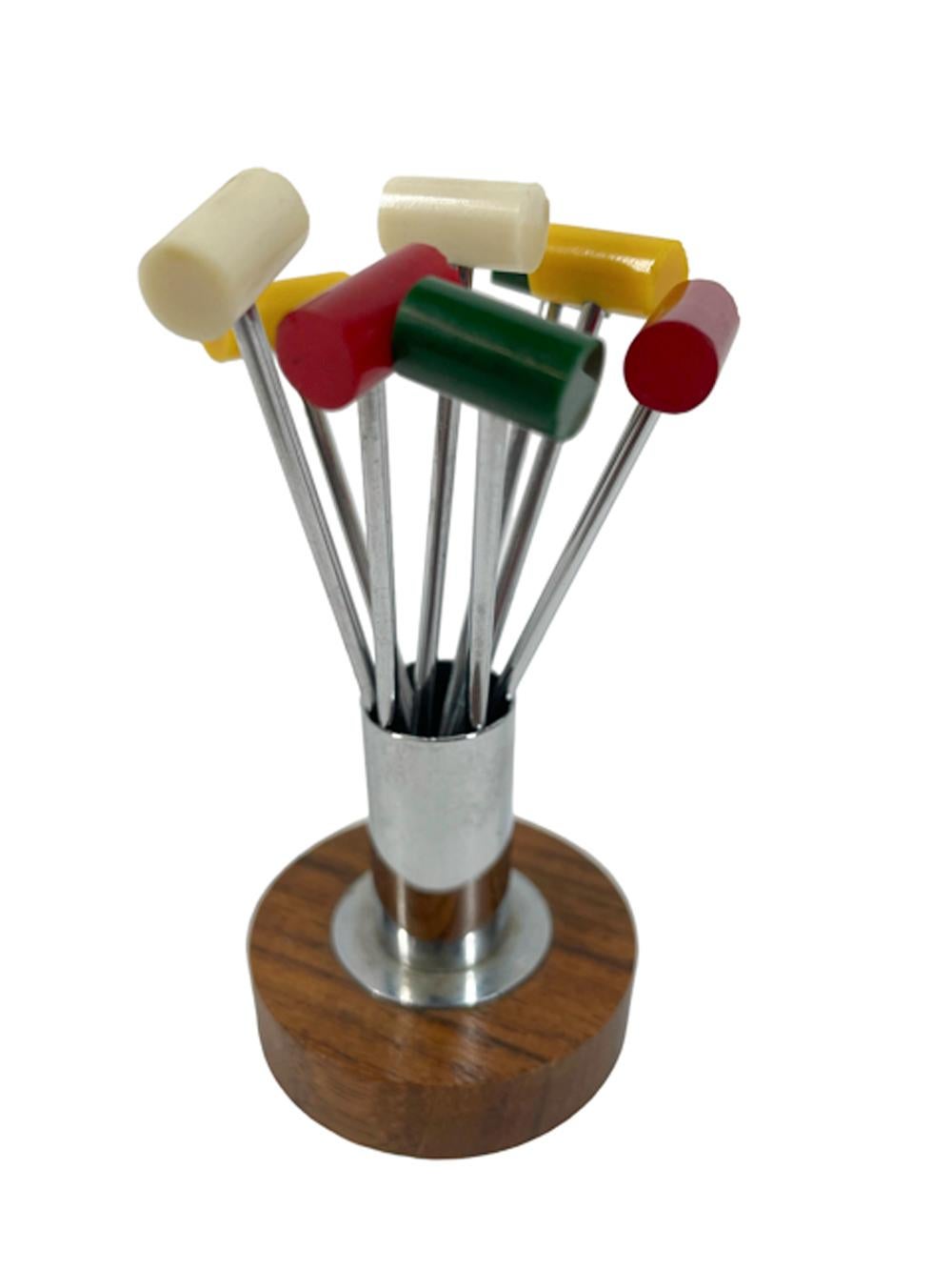 Eight Art Deco cocktail picks in the form of polo or croquet mallets with forked tips and Bakelite heads (two each of four colors) in a stand made as a chrome cylinder atop a disk of wood.