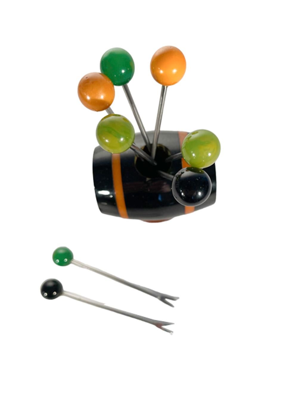 Art Deco whiskey keg cocktail pick set, the 8 picks with Bakelite ball tops, 2 each of four colors stand in a dark brown Bakelite keg with butterscotch bands which rests on its side atop a cylindrical dark brown base with an round amber foot.
