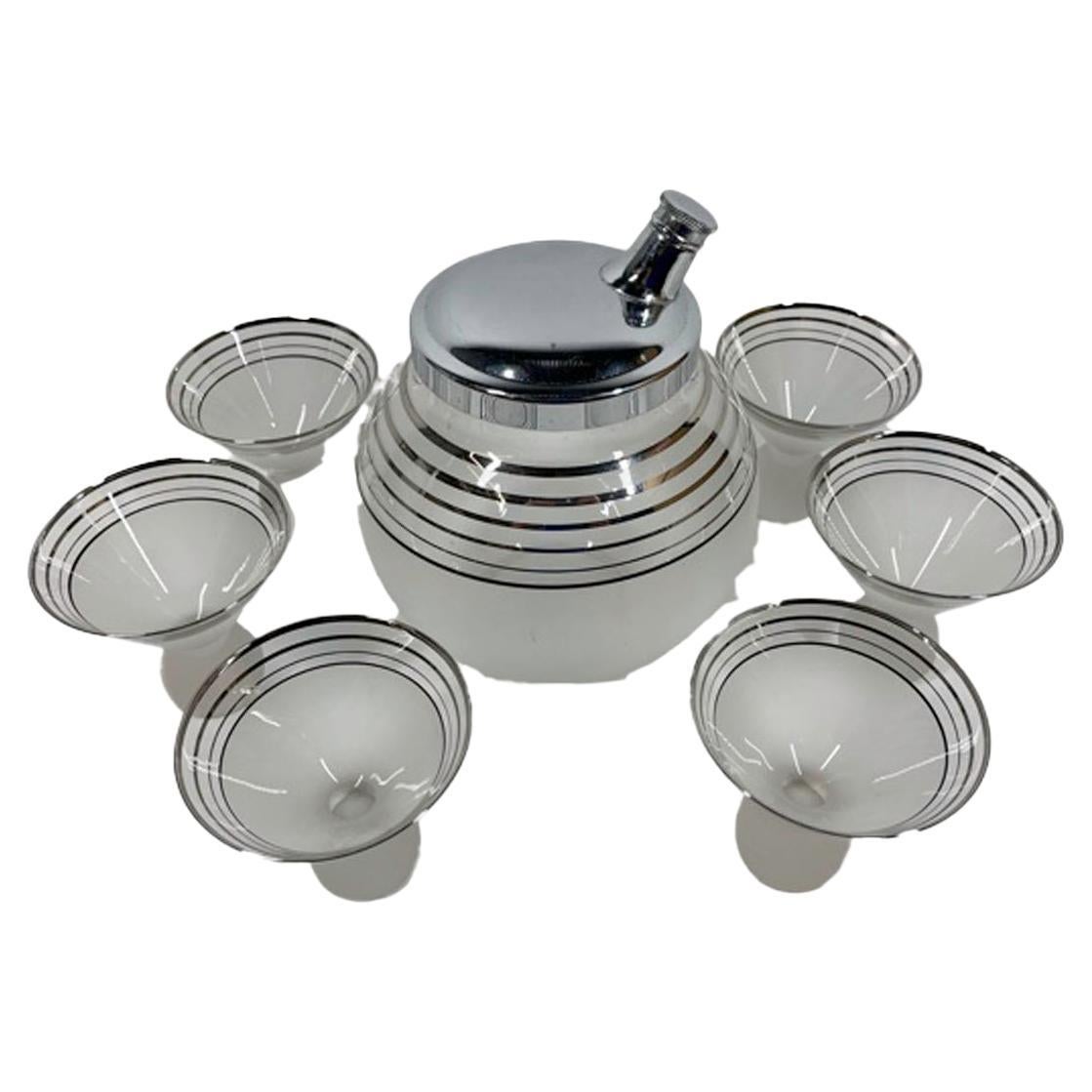 Art Deco cocktail shaker set with a ball-form shaker and 6 cocktail glasses with cone shaped bowls on ball feet. Each piece with silver bands on clear glass above a frosted lower section.