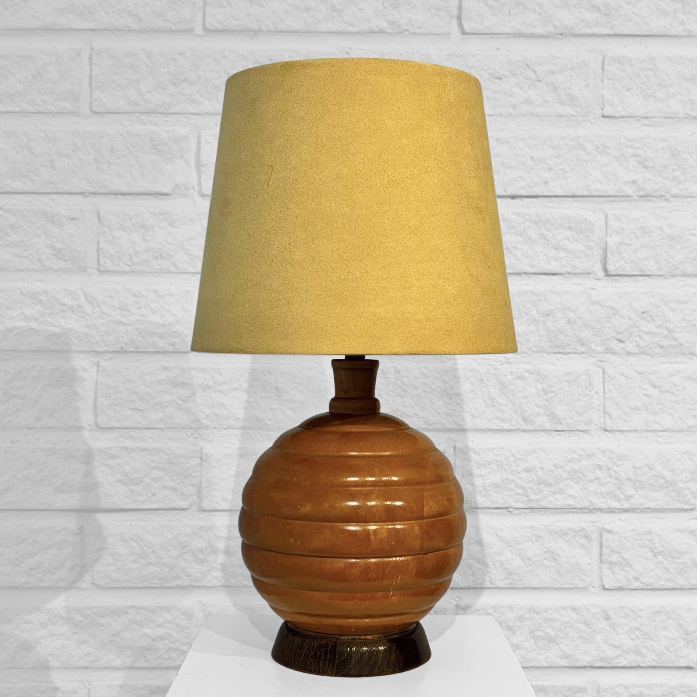 Lampe géométrique Art déco fabriquée en bouleau massif, avec une base en forme de boule ornée de douces lignes horizontales. La lampe est équipée d'une douille en laiton avec des raccords en porcelaine et un interrupteur intégré. Il est accompagné