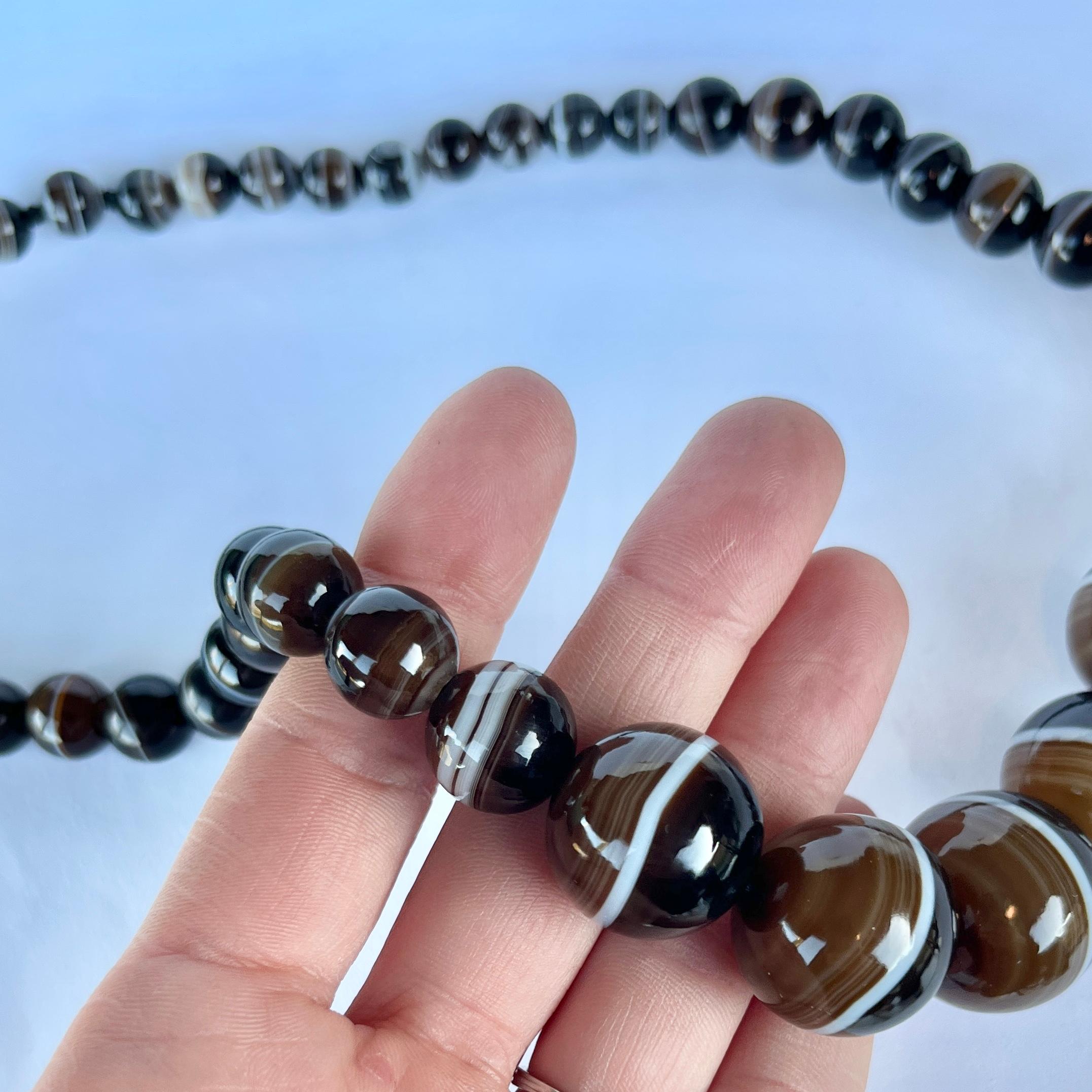 The banded agate beads which make up this necklace are a mix of black and brown with all tones in-between! The bright white rings around the beads curve and wave and are beautiful. 

Length: 50.5cm
Bead Diameter: 22-8mm

Weight: 105g