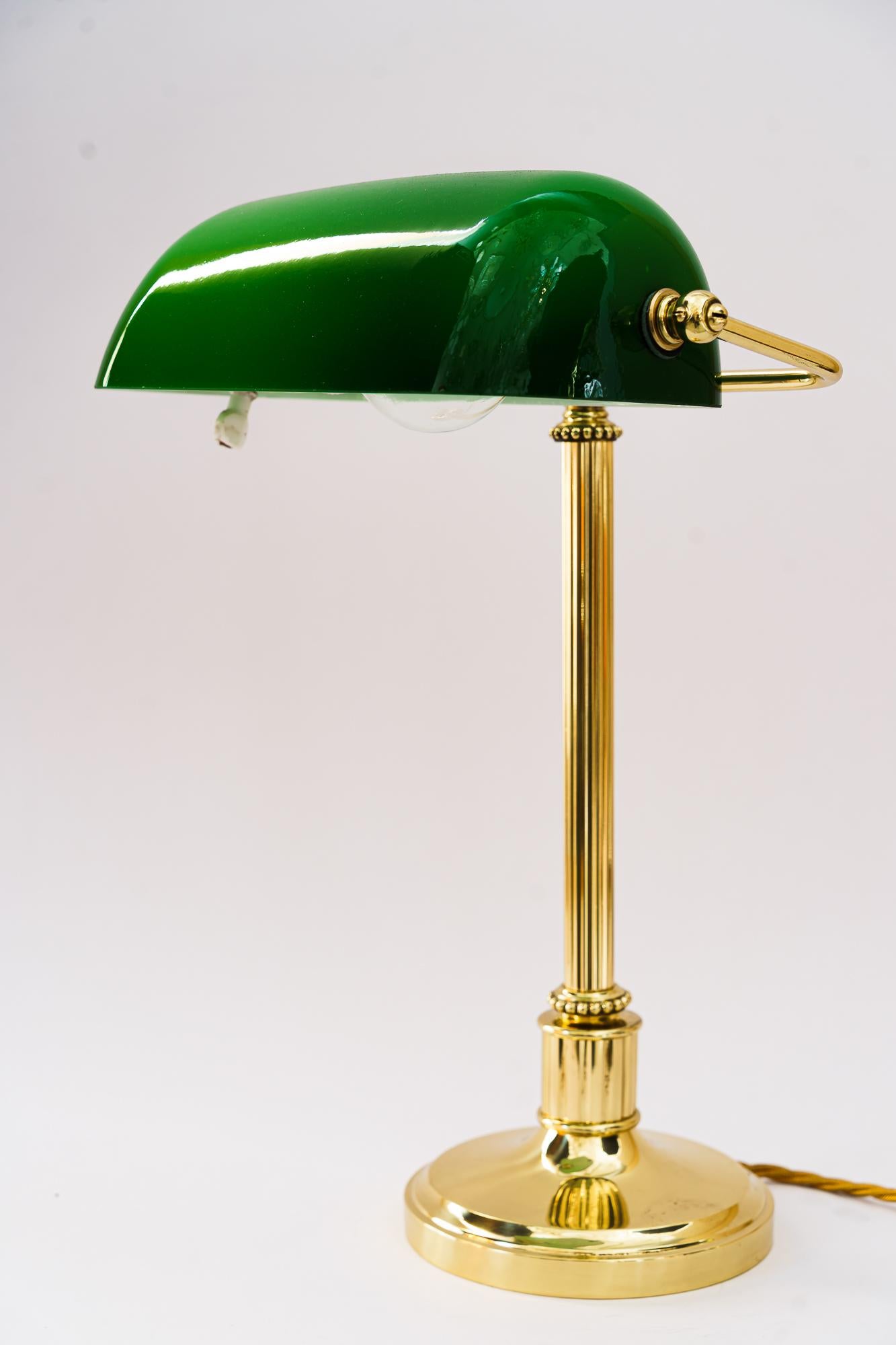 Art deco banker lamp with green glass shade, Vienna, around 1920s.
Brass polished and stove enameled.
Original glass shade.