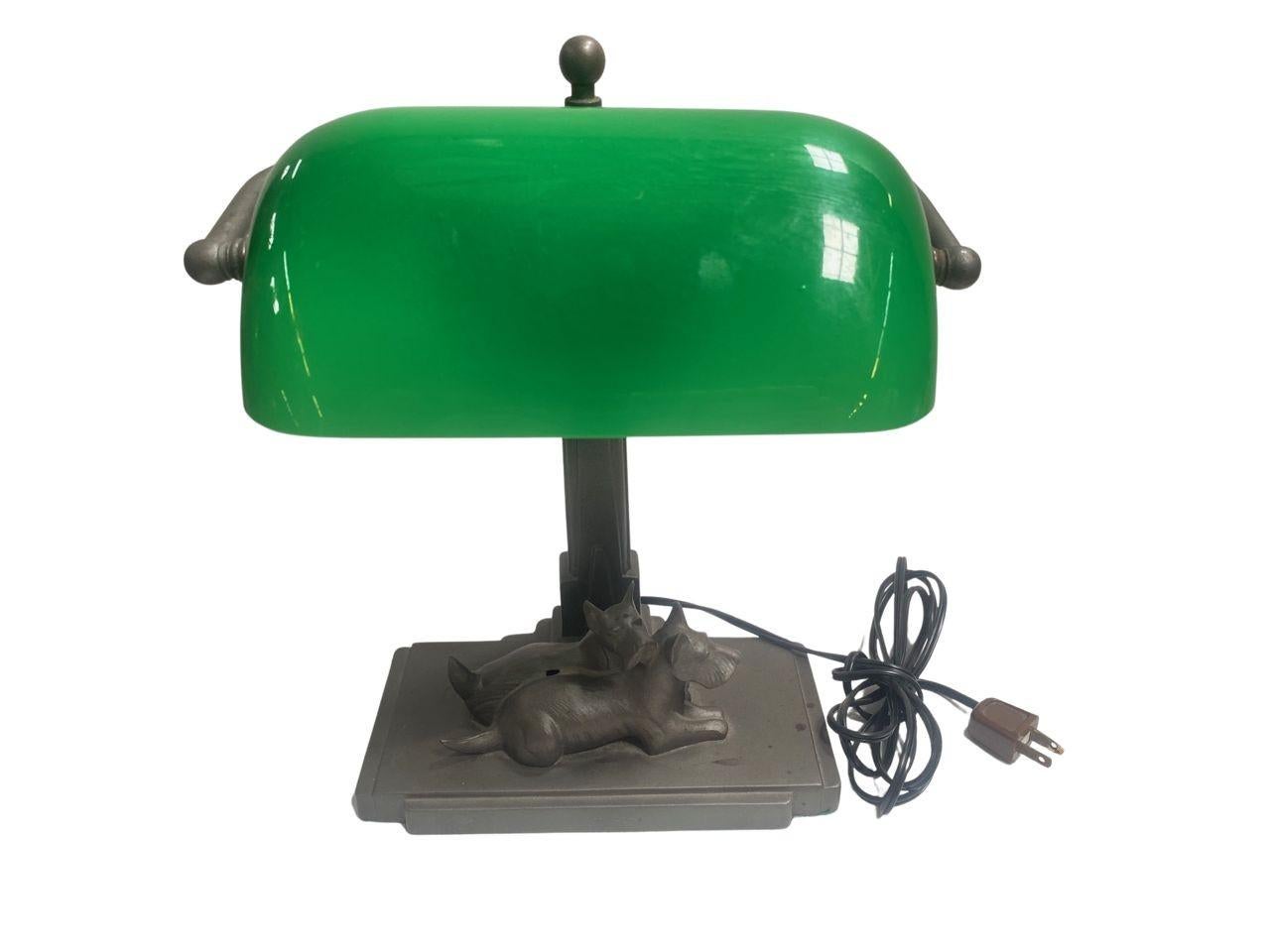 Rare Art Deco Bankers Light with Art Deco design, with a pair of Scottish terrier dogs under the vivid Green glass bankers light.Great detail of the brow of the Scottie to the stem of the lamp with a skyscraper design.
 
The lamp is signed on the