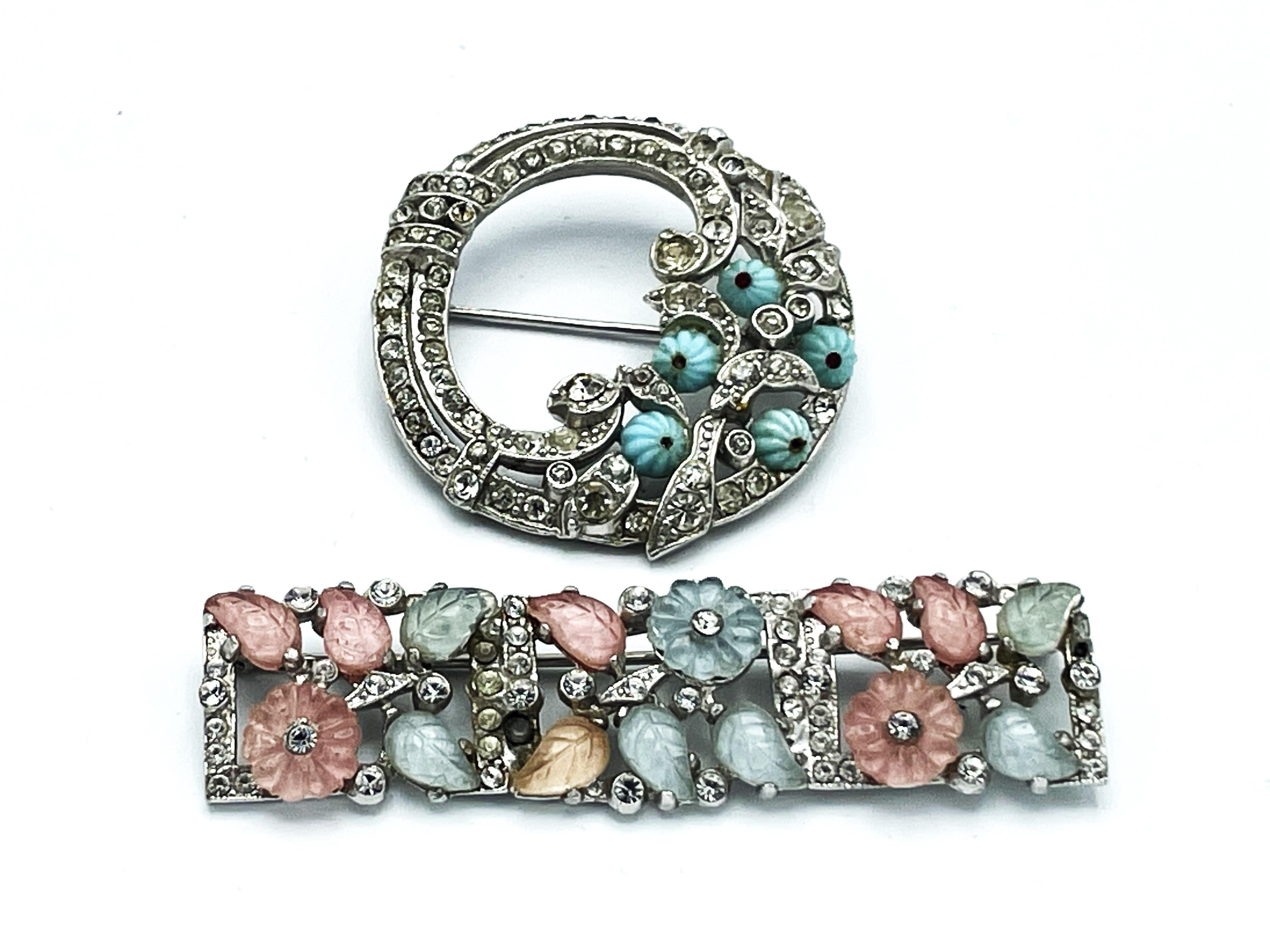 
A narrow bar brooch with rose and light blue glass flowers and small leaves, surrounded by many small rhinestones. The small flowers and leaves were not ground, but the liquid glass was poured into the mold. Made in the USA 1940s.
A rhinestone is