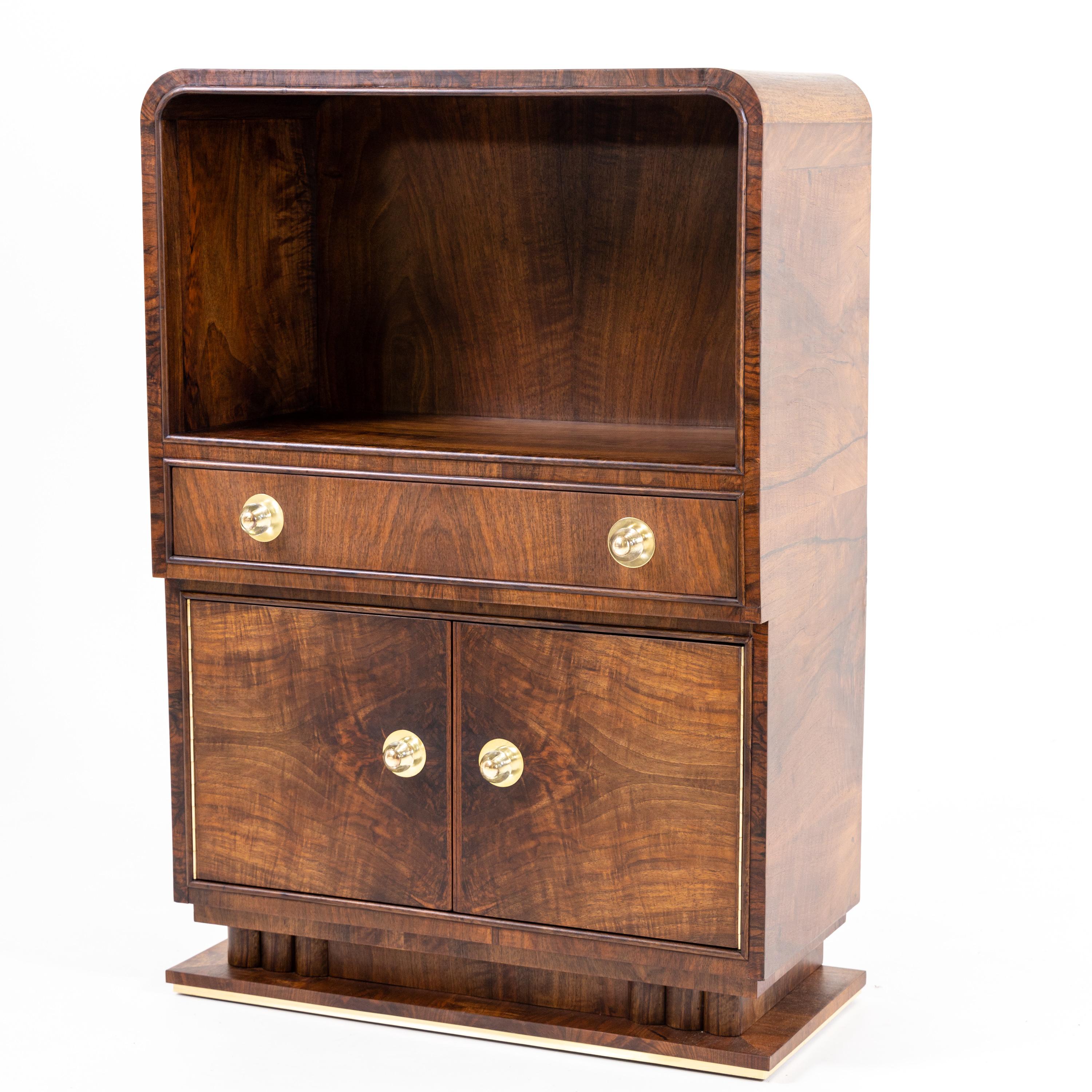 Art Deco bar cabinet with two doors and wide drawer with polished brass knobs. The body is veneered in walnut.