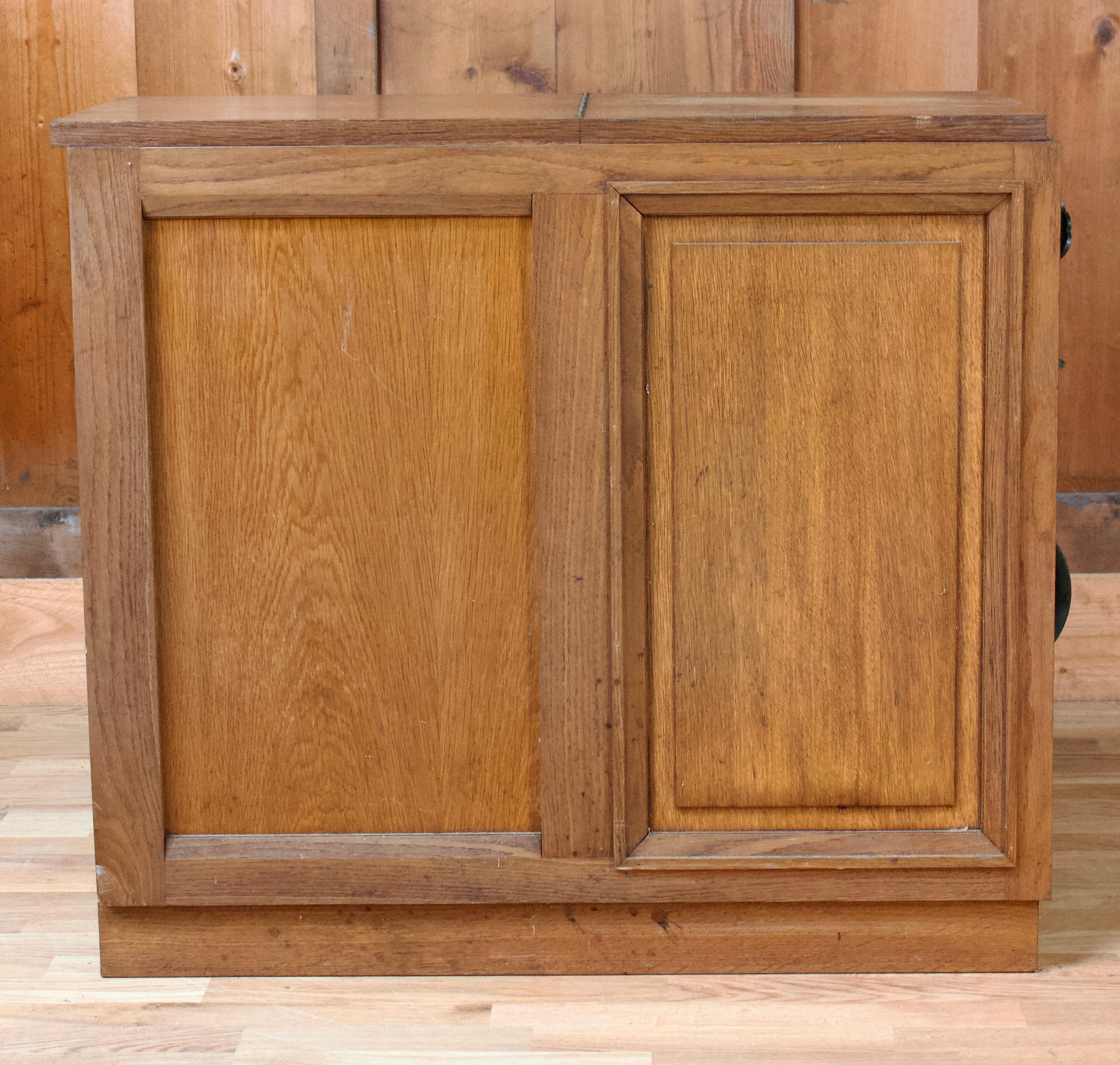 Wooden bar from the Art Deco period which opens in two parts. The upper part opens with a lid and reveals a compartment entirely covered with mirrors, provided for storing glasses, bottles... The lower part is divided into two parts in which there