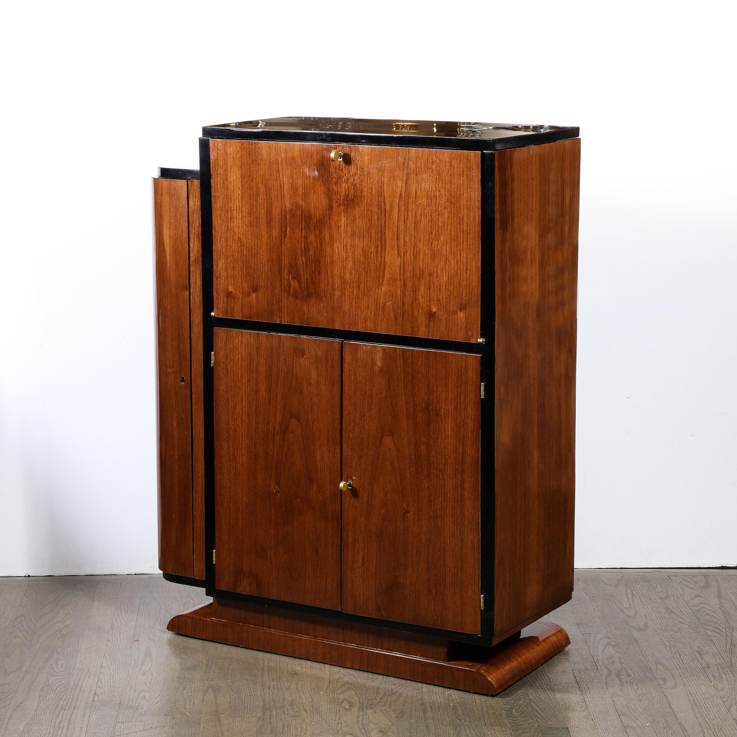 This beautifully proportioned and finished Art Deco Machine Age Bar Cabinet in Book-matched Walnut with Black Lacquer Accents originates from the United States, Circa 1935. This Bar Cabinet features highly thoughtful design and material execution,