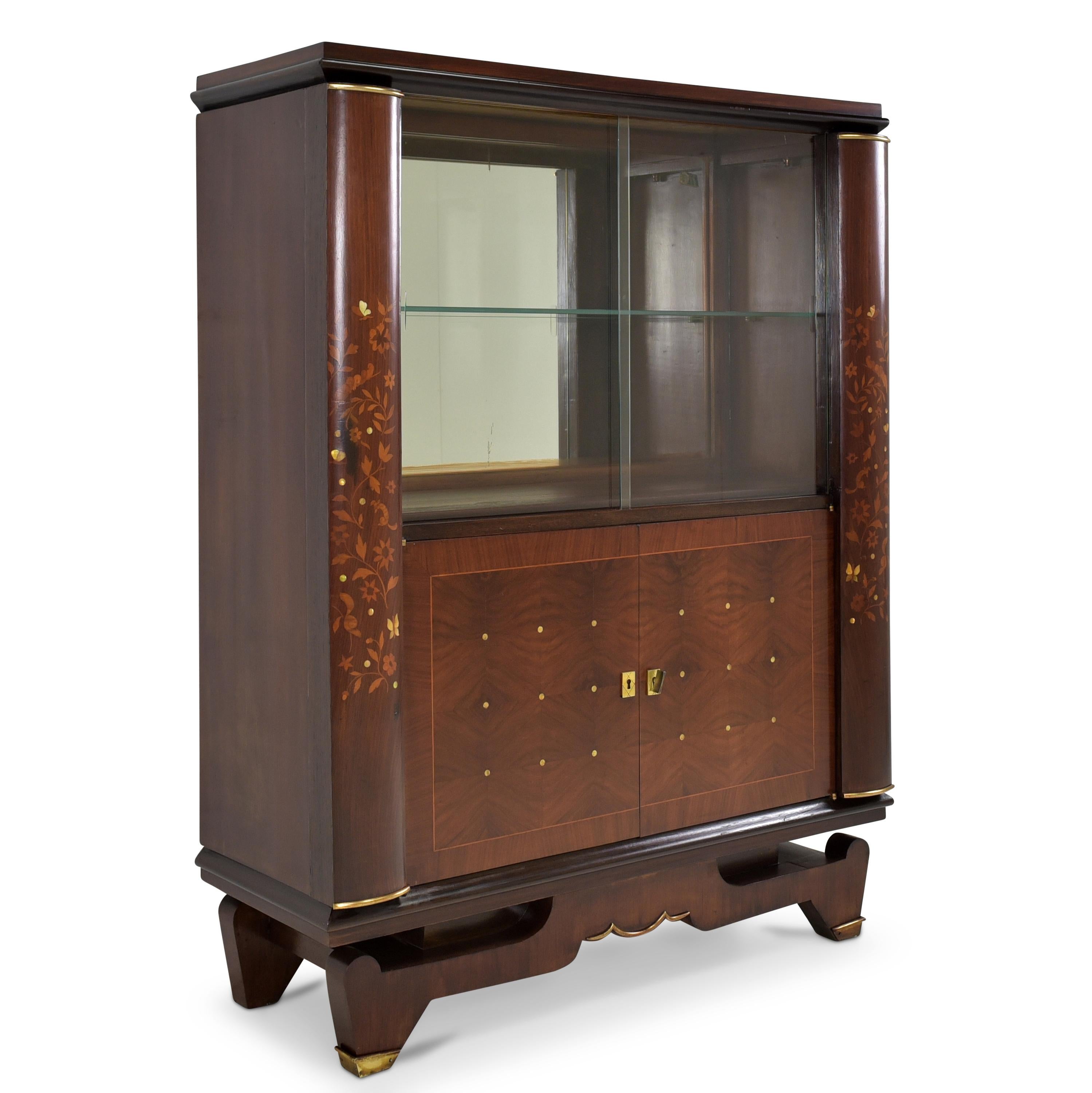 Showcase restored Jules Leleu Art Deco bar cabinet mahogany France

Features:
Sliding door compartment with glass shelf at top, two doors at bottom
Very high quality processing
Elaborate inlaid work with shimmering mother-of-pearl
Original