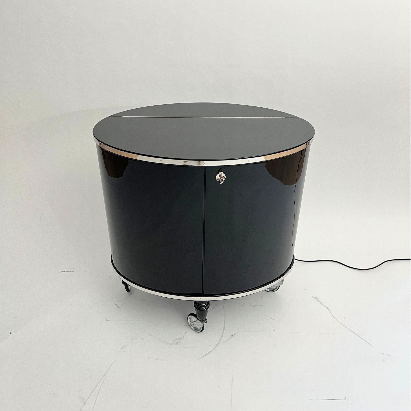 Amazing original, restored Art Deco bar car or bar trolley in black piano lacquer with mirrored interior.
Oval shape with hinged doors and movable on 4 wheels.
Walnut wood, black lacquered and polished. Top and bottom with all-round stainless steel