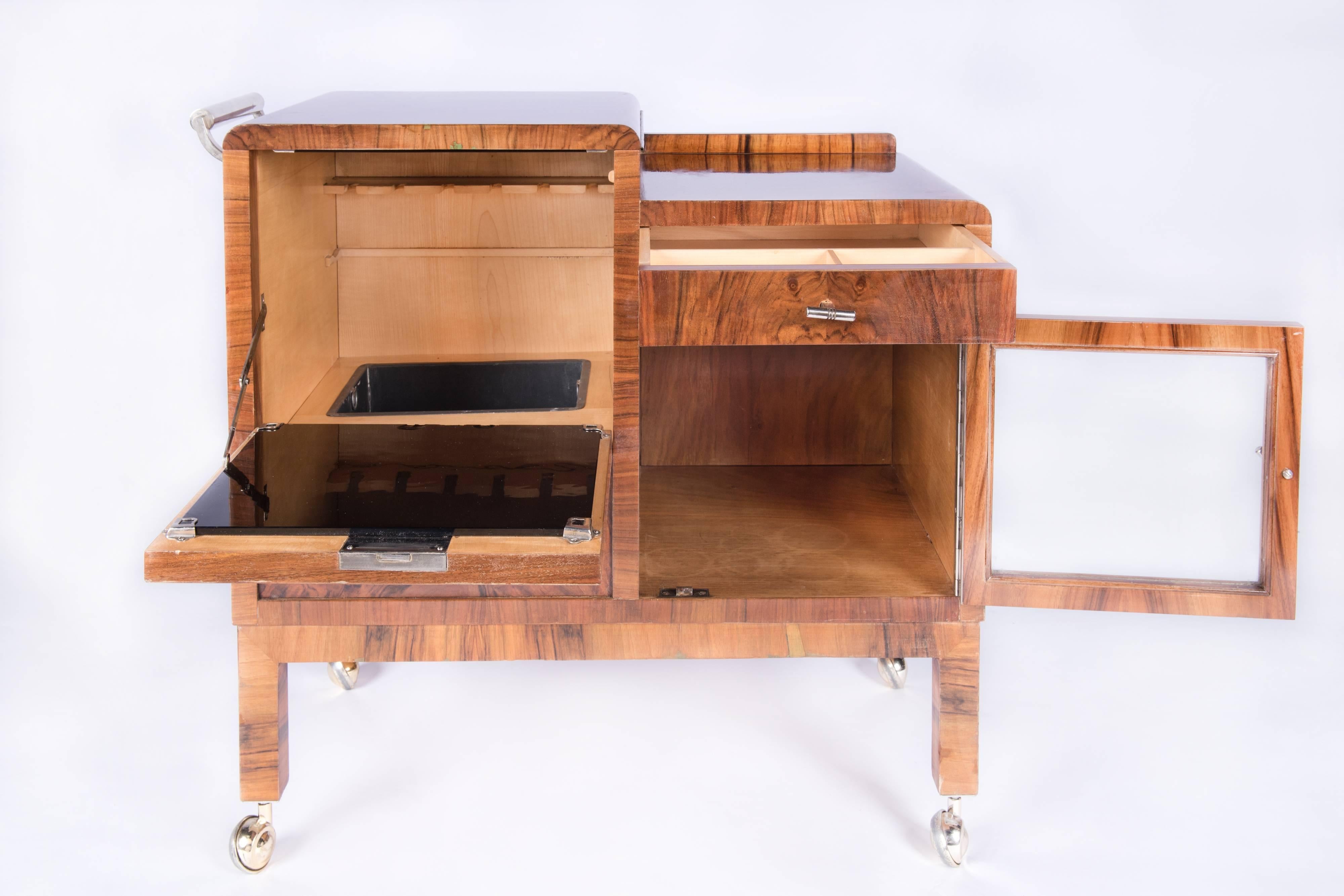 Walnut Art Deco rolling bar cart, restored with hand made lustrous French polish .A cabinet for the bottles on the left hand side and smaller display cabinet for the glasses and a small drawer on the right hand side. Very pretty.

 